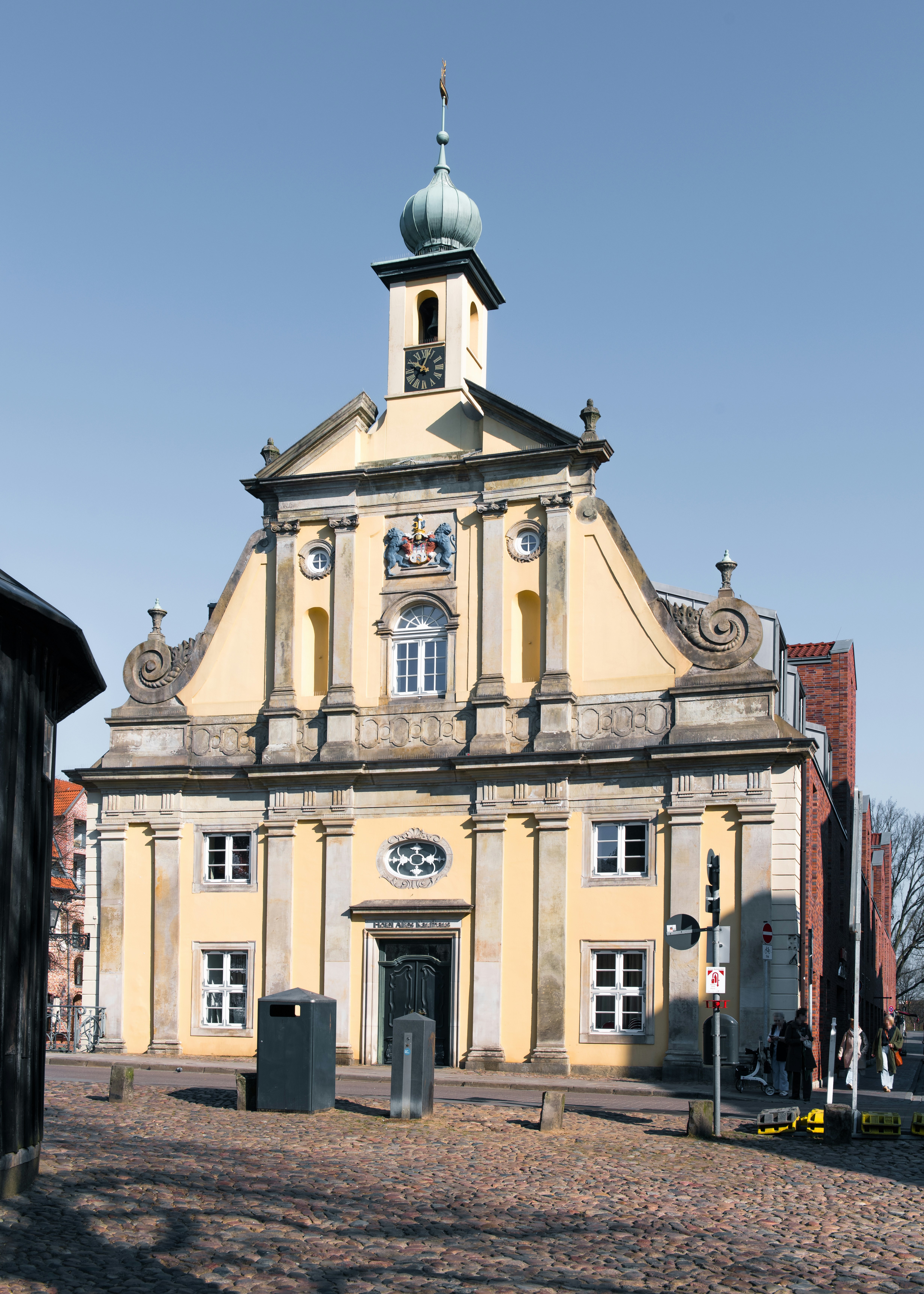 A yellow building stands tall in a sunny square.