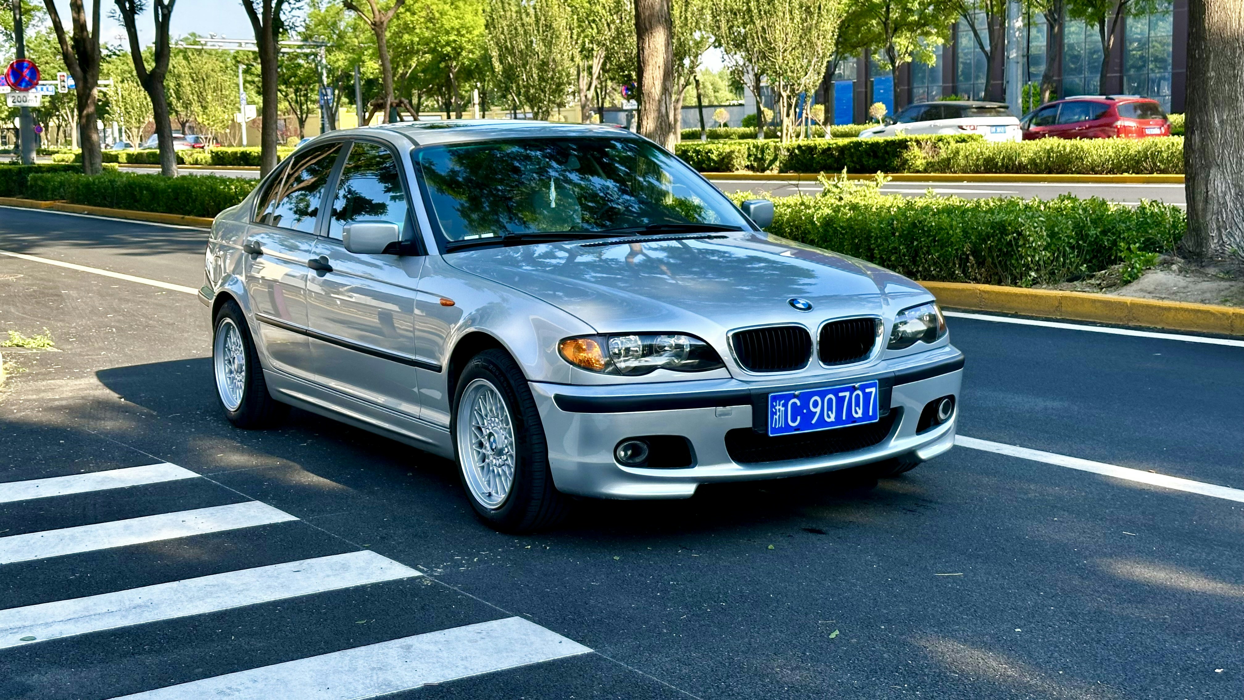 A silver BMW car is on a crosswalk.