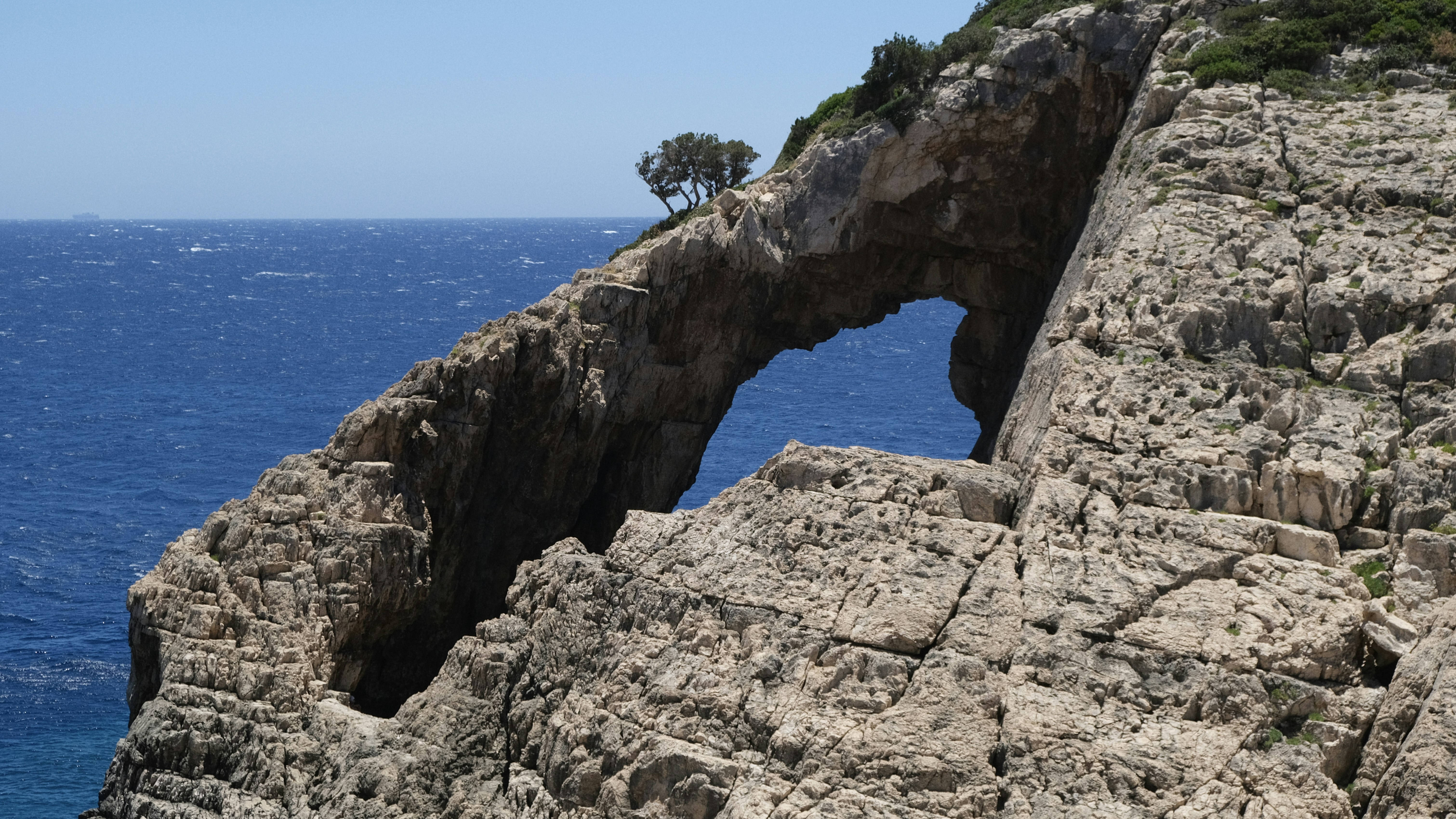 A rocky cliff has a natural archway.