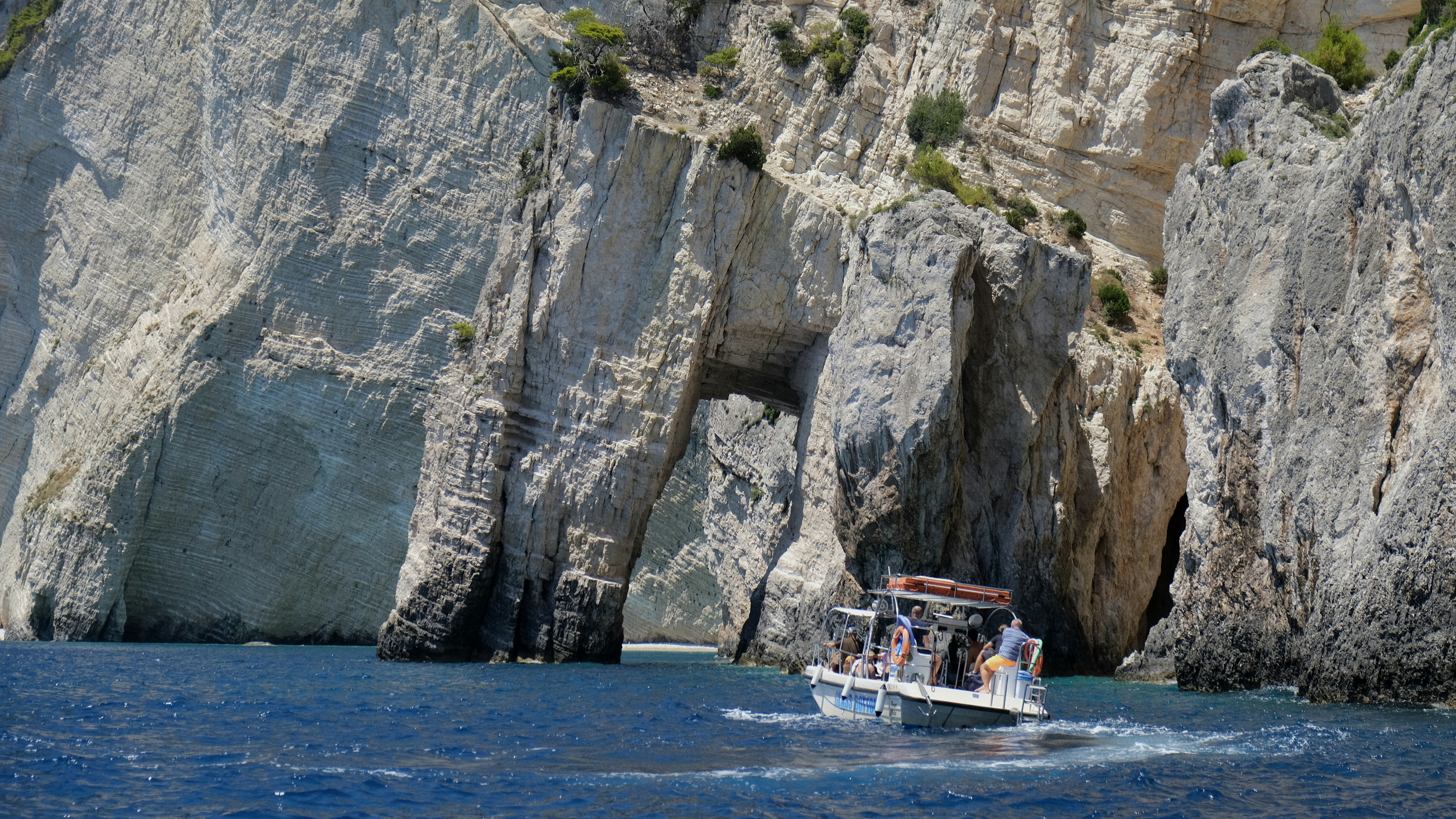 A boat sails through a coastal archway.