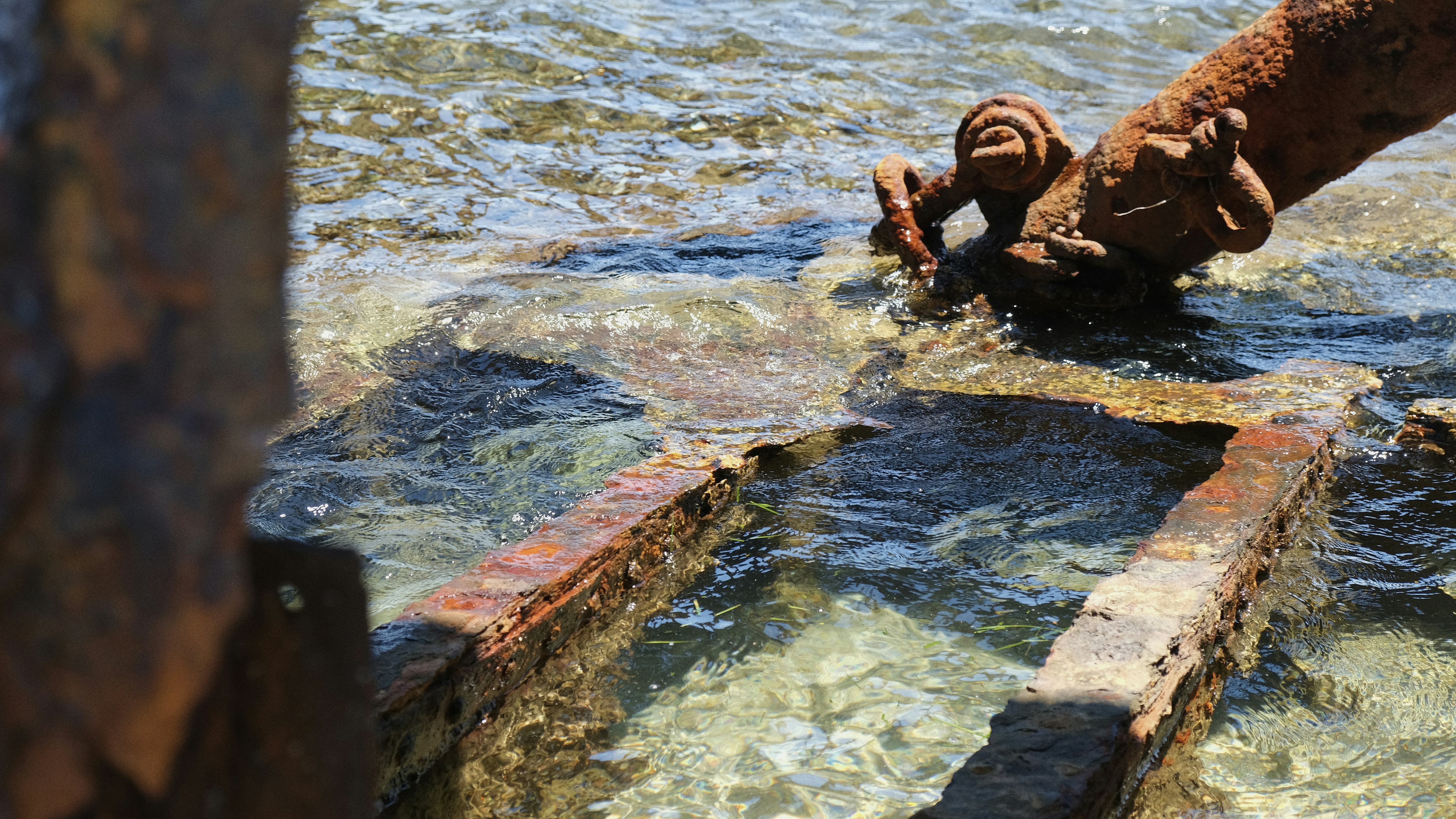 Rusty metal parts submerged in the clear water.