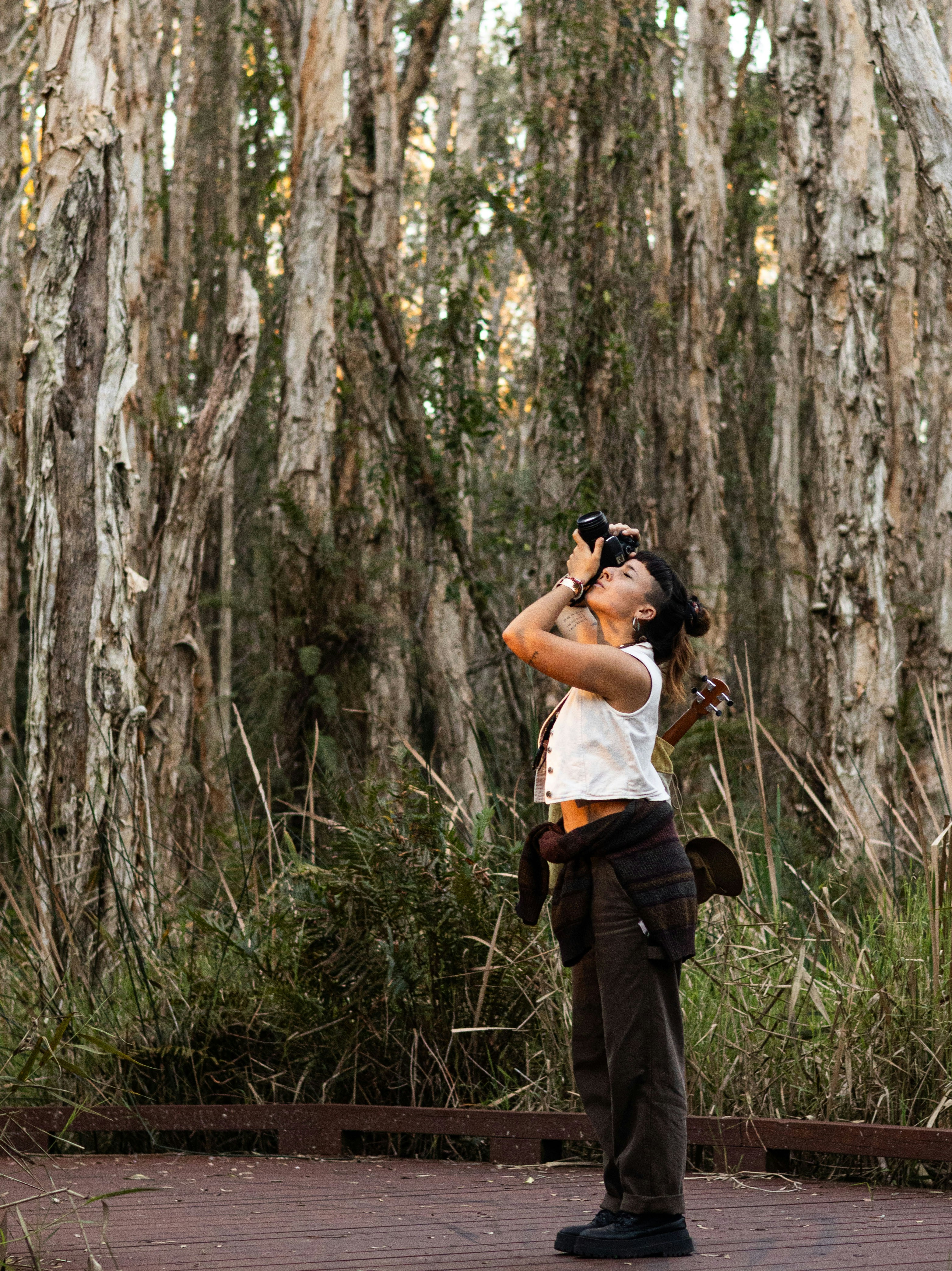 A woman photographs in a dense forest.