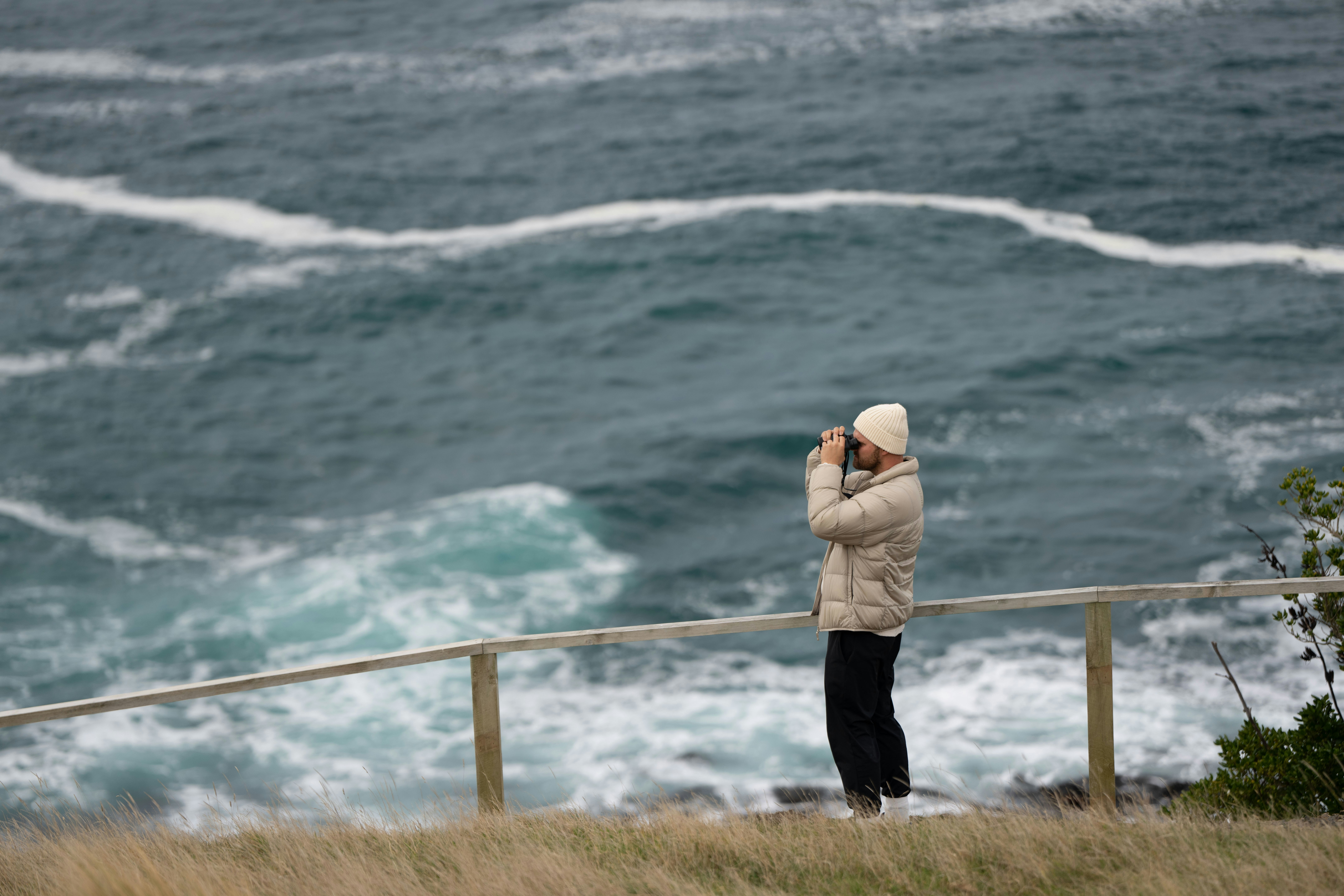 A person photographs the wavy ocean.