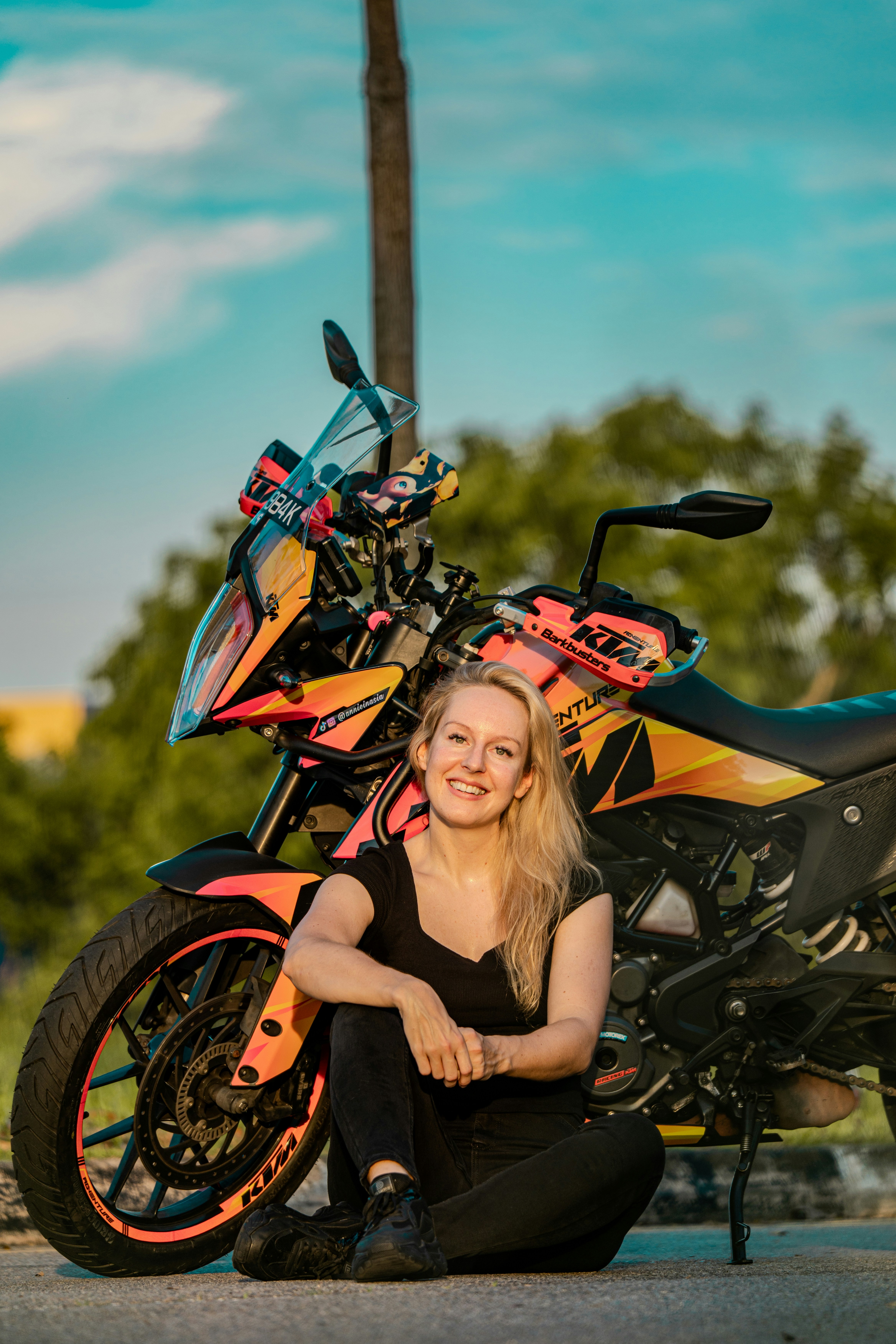 A woman poses with her motorcycle.