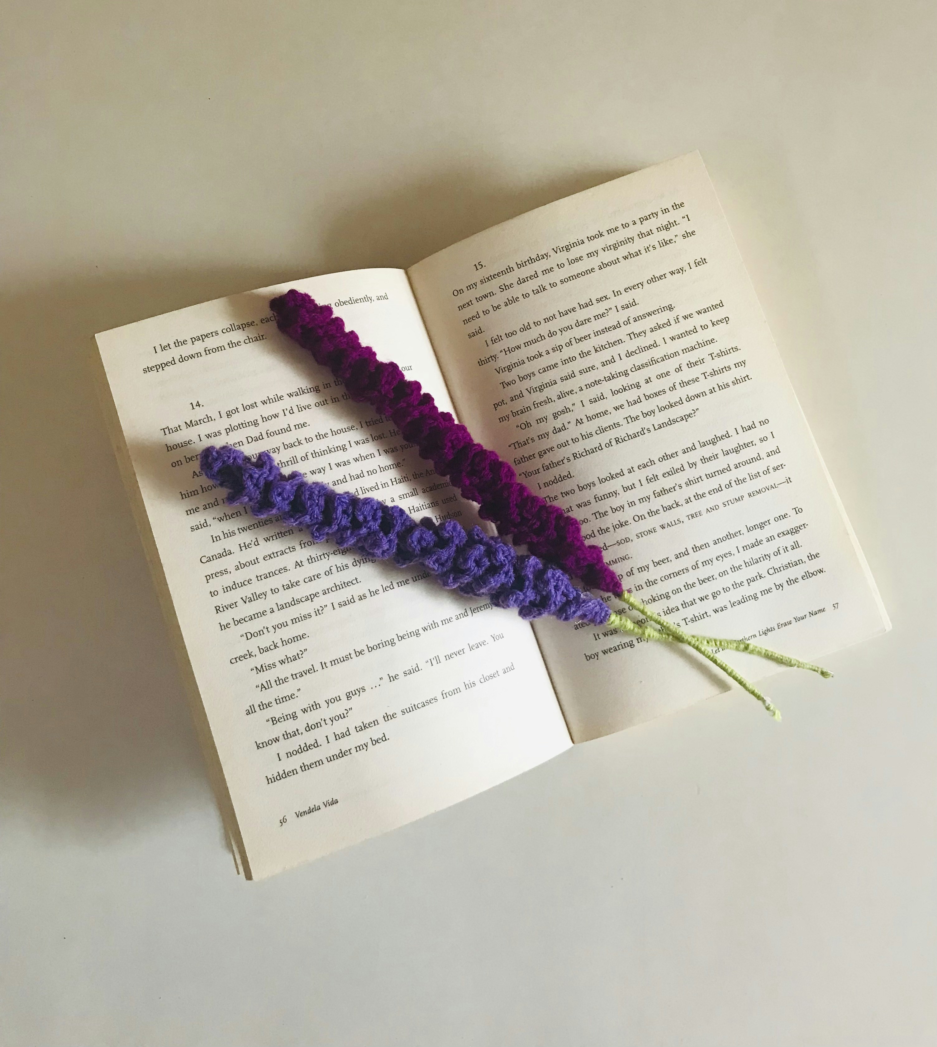 Crocheted flowers rest on an open book's pages.