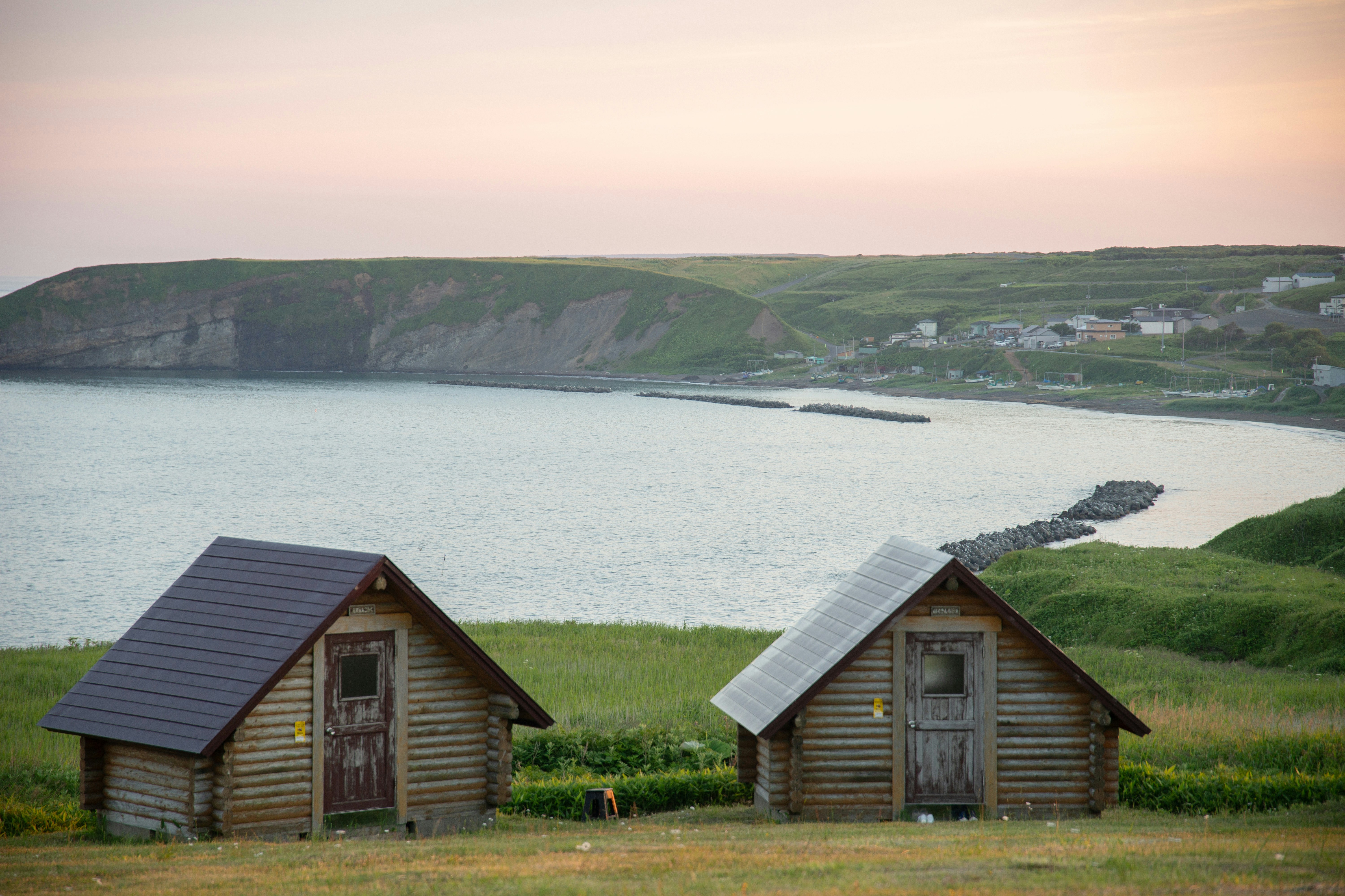 Two small cabins sit near the serene coastline.