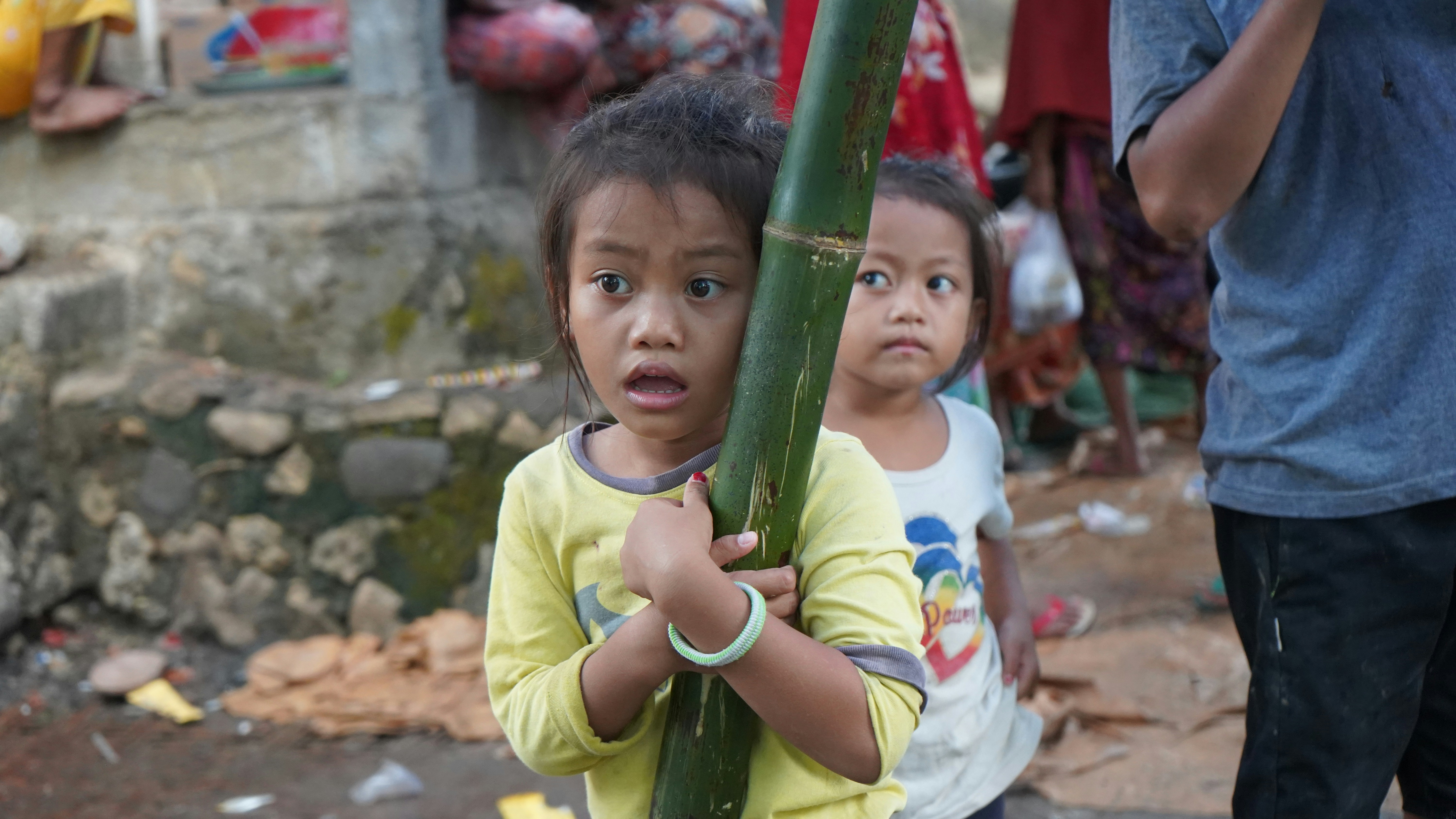 Two young girls look startled while holding bamboo.