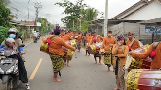 People in traditional attire march down a road.