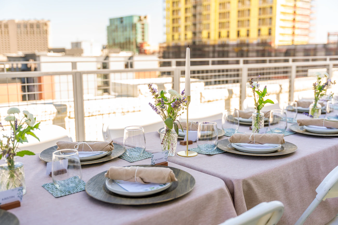 A rooftop table set for a group dinner in the afternoon sun