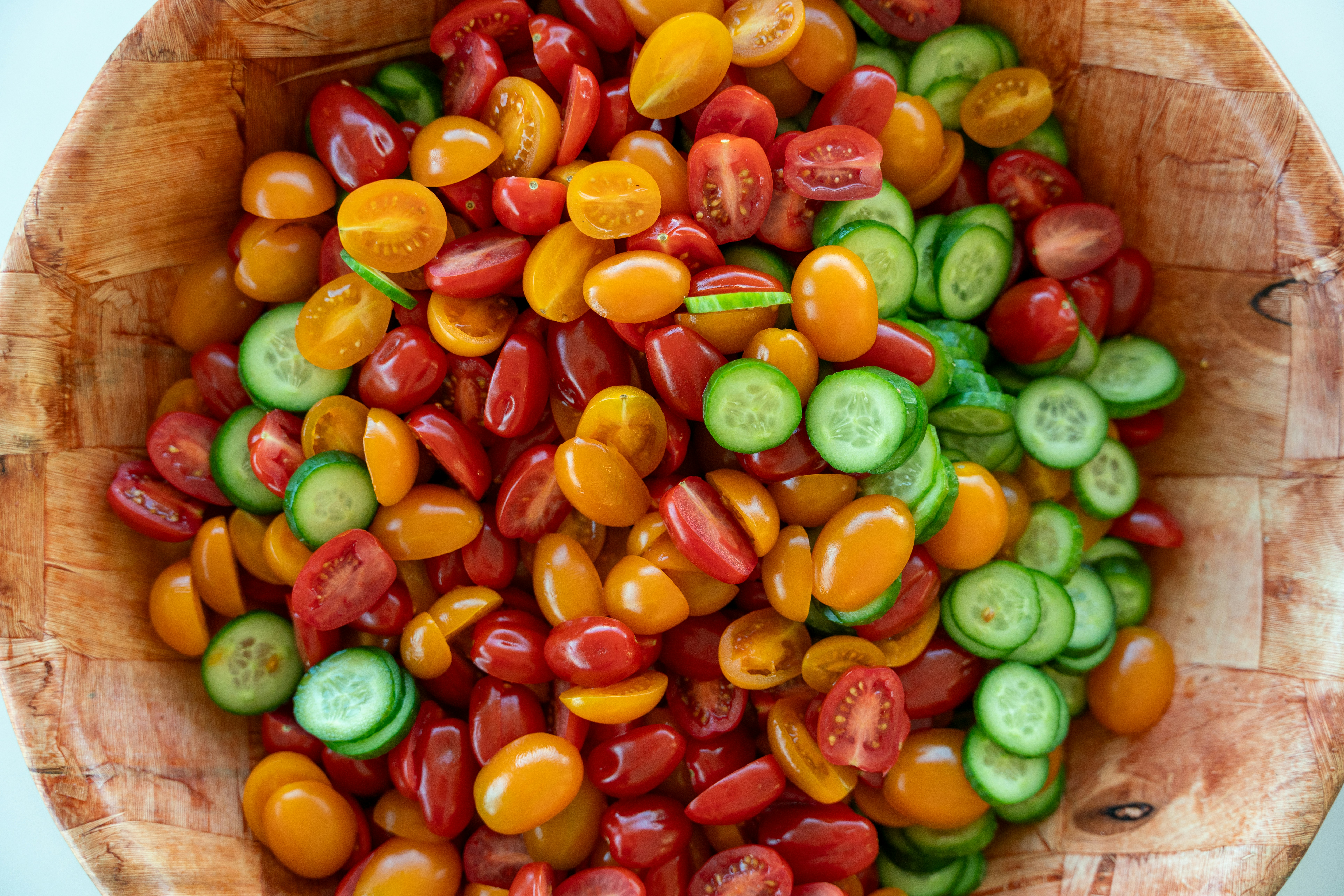 Vibrant cherry tomatoes and cucumbers in wooden bowl