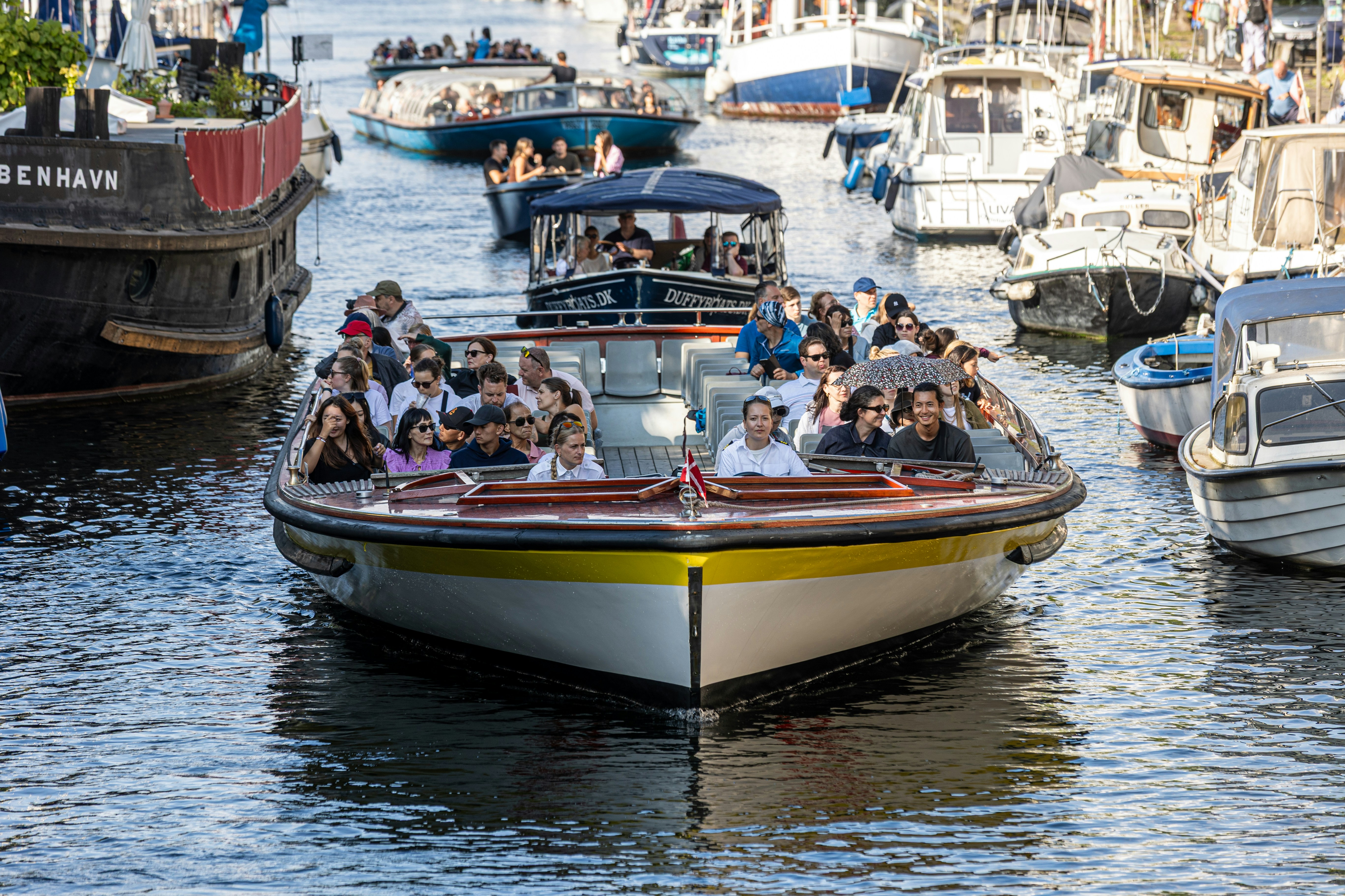 Boats cruise through a canal packed with tourists.
