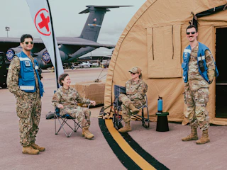 Military personnel pose near a medical tent and plane.