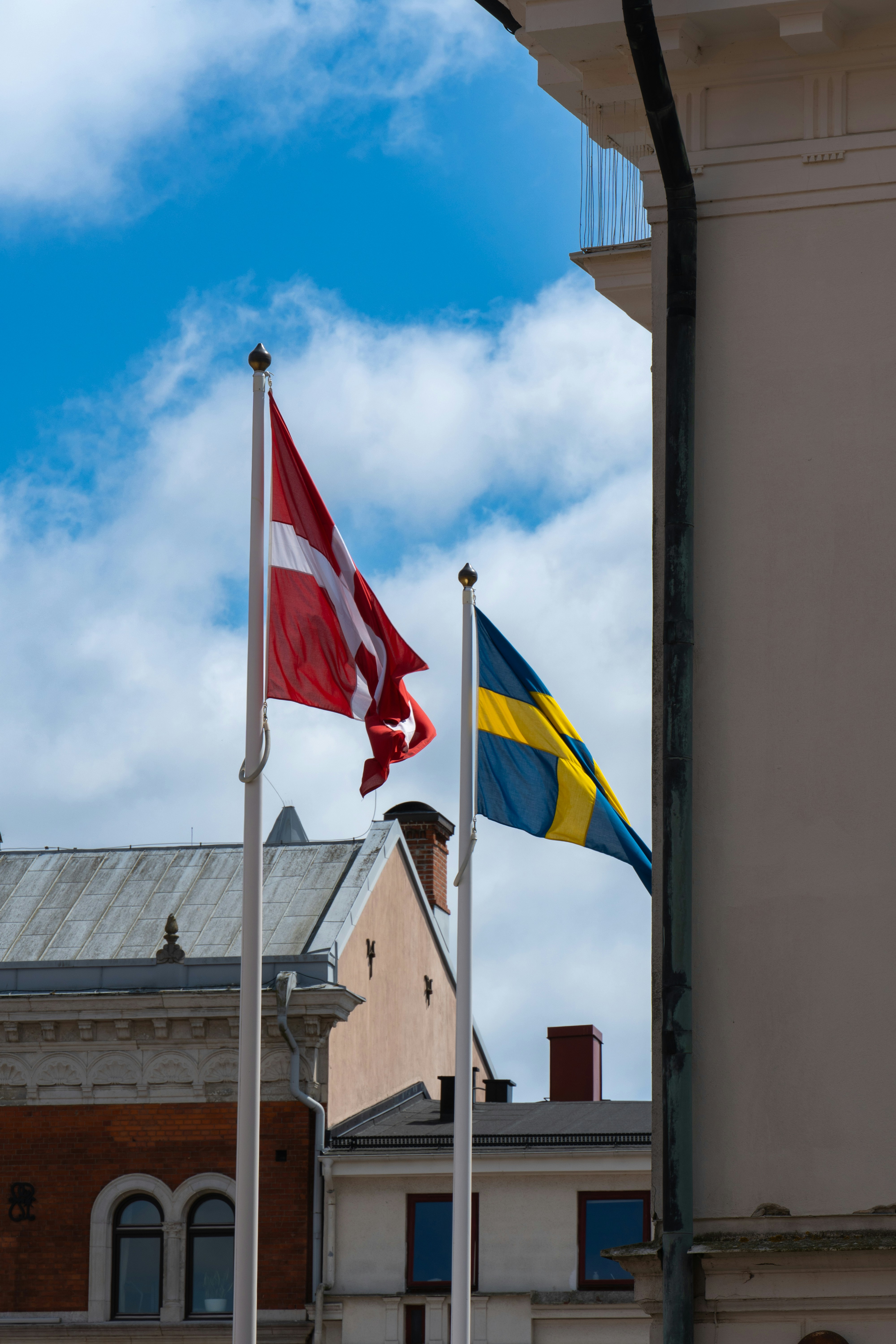 Flags of denmark and sweden flutter in the wind.
