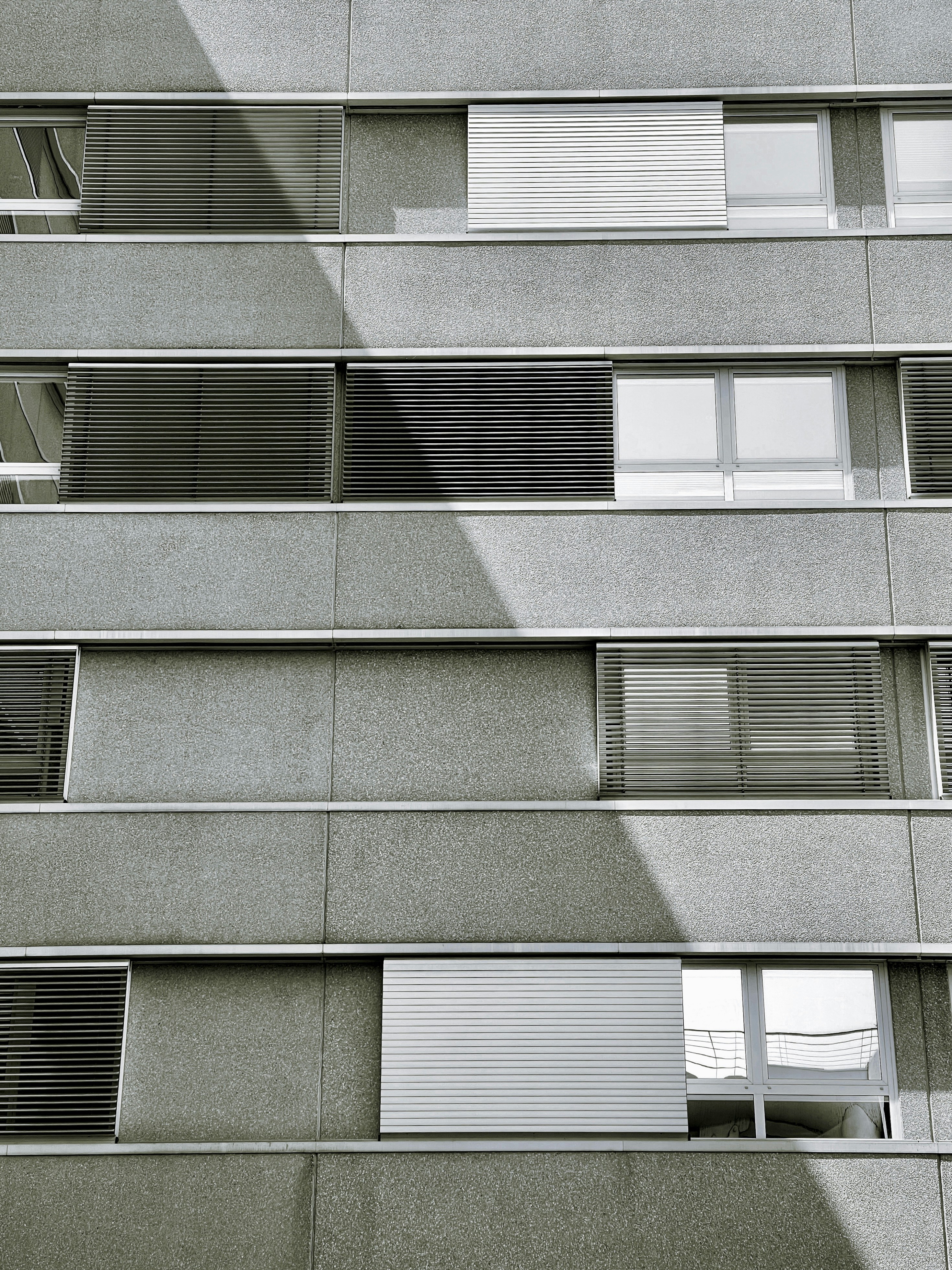 Concrete building with rows of windows and shadow.