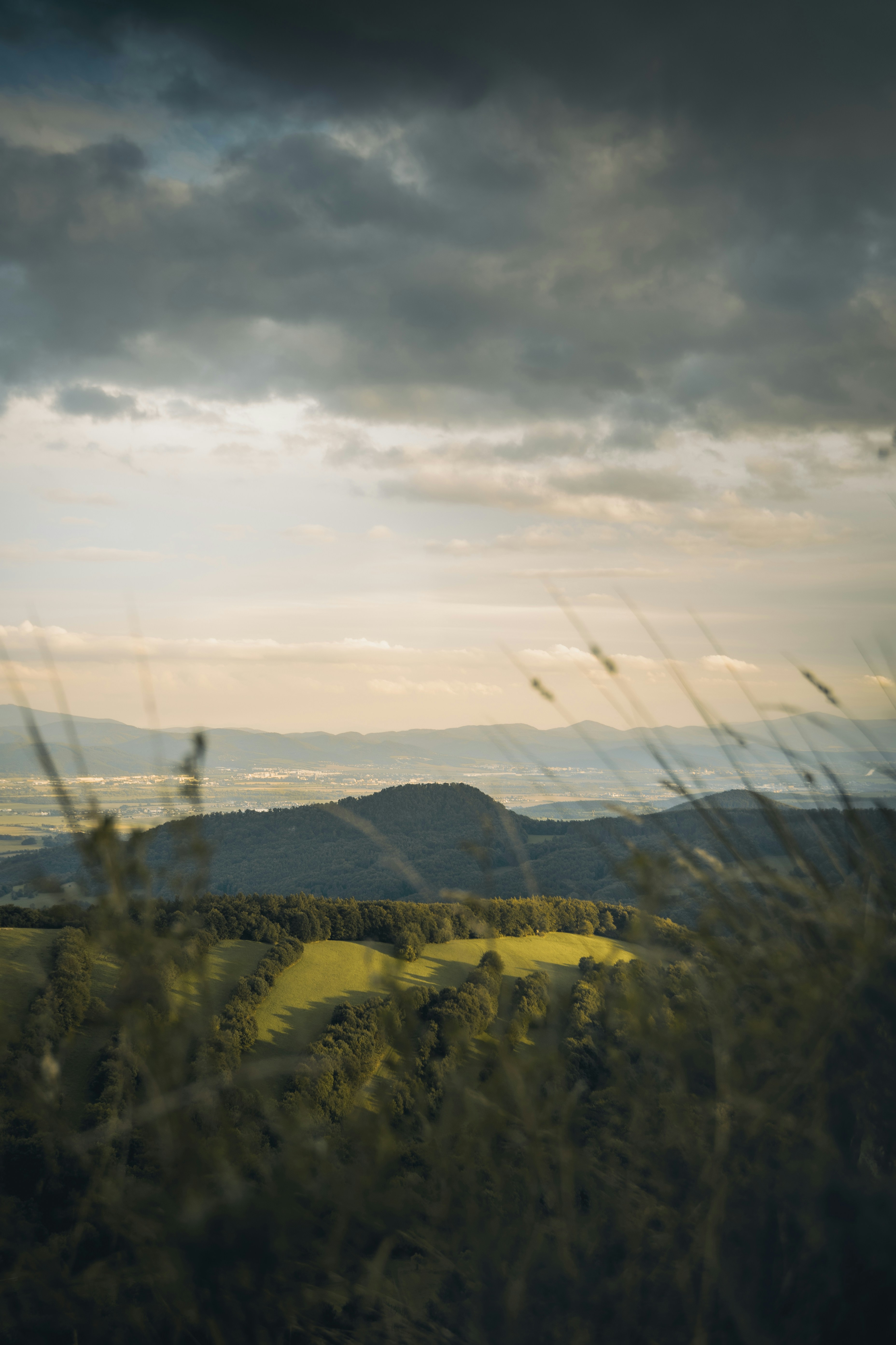 Dramatic clouds hover over rolling green hills.