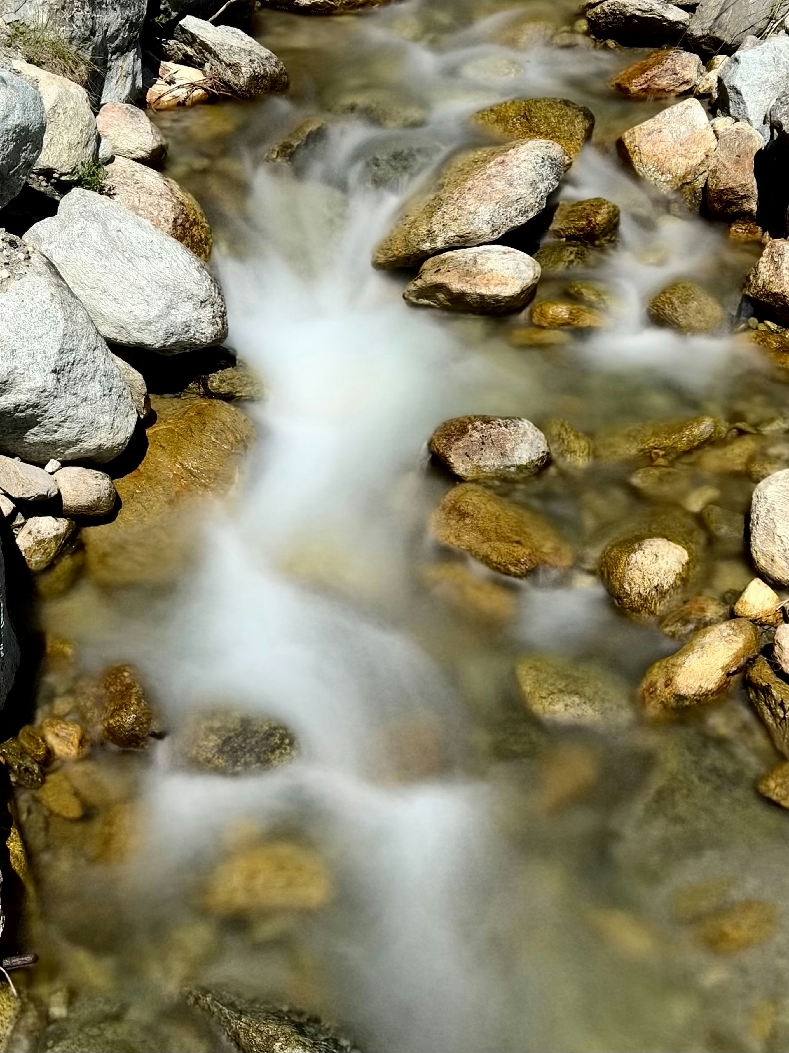 Water flows smoothly over rocks in a stream.