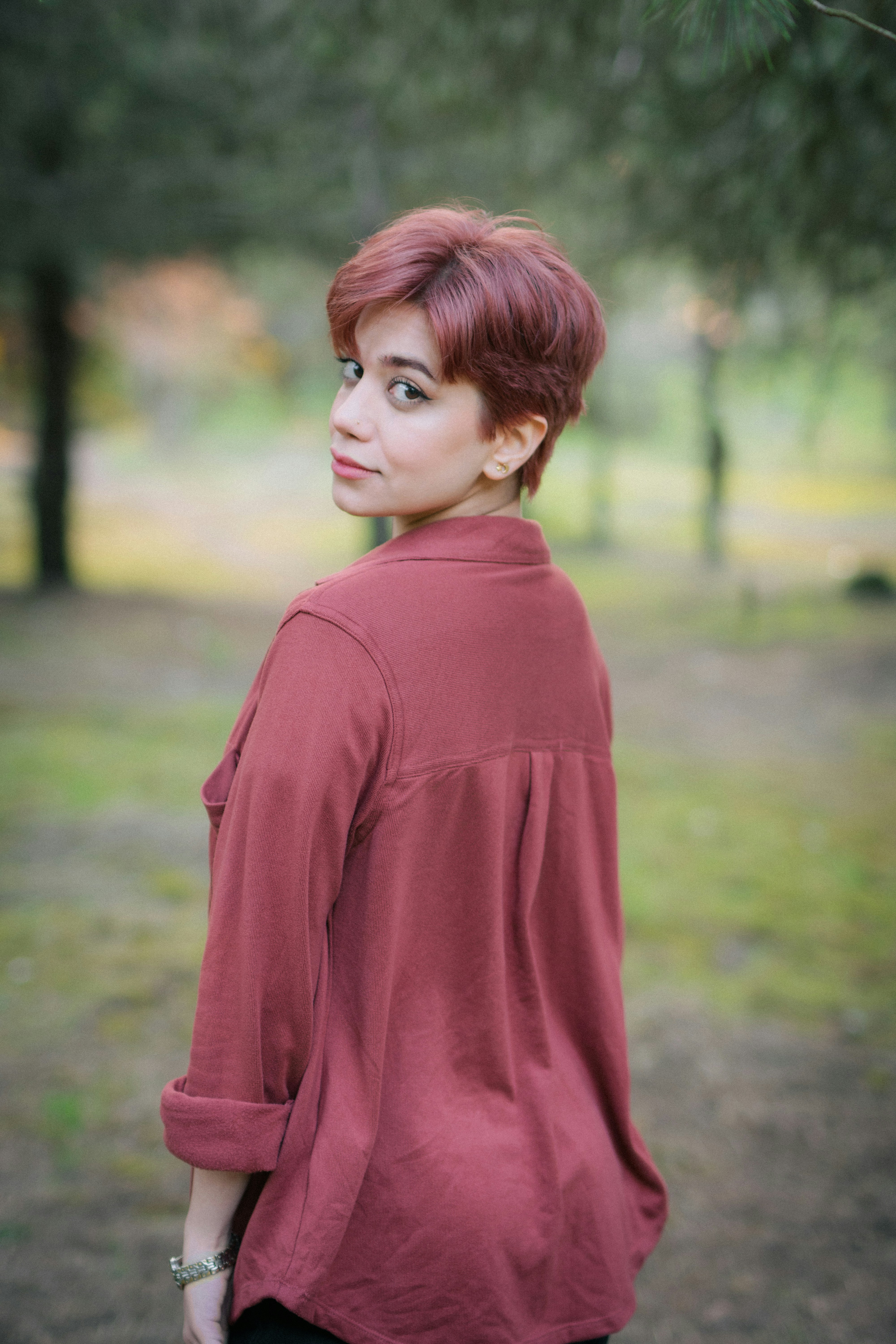 Woman with short red hair looks over her shoulder.
