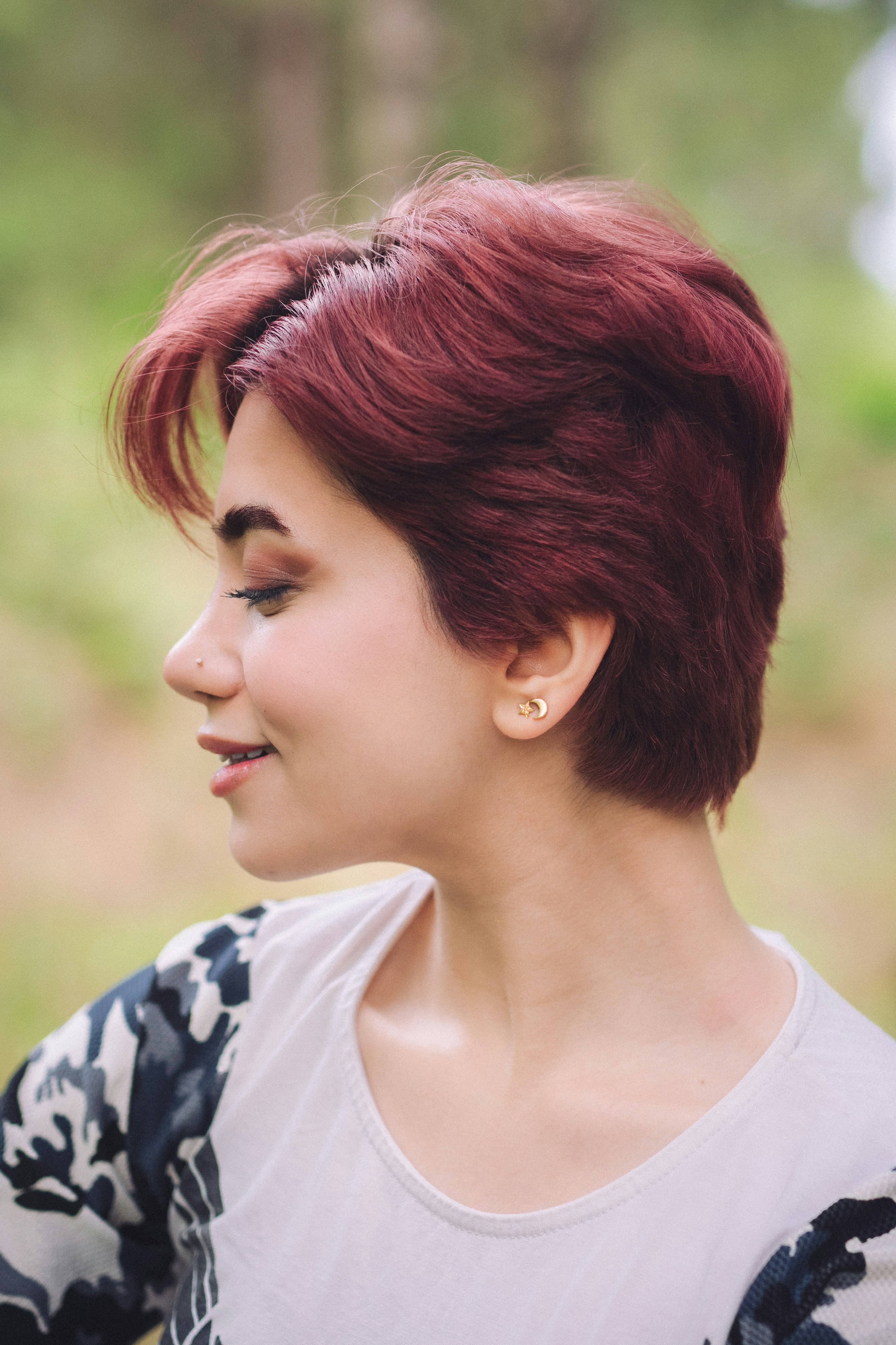 A woman with red hair smiles outside.