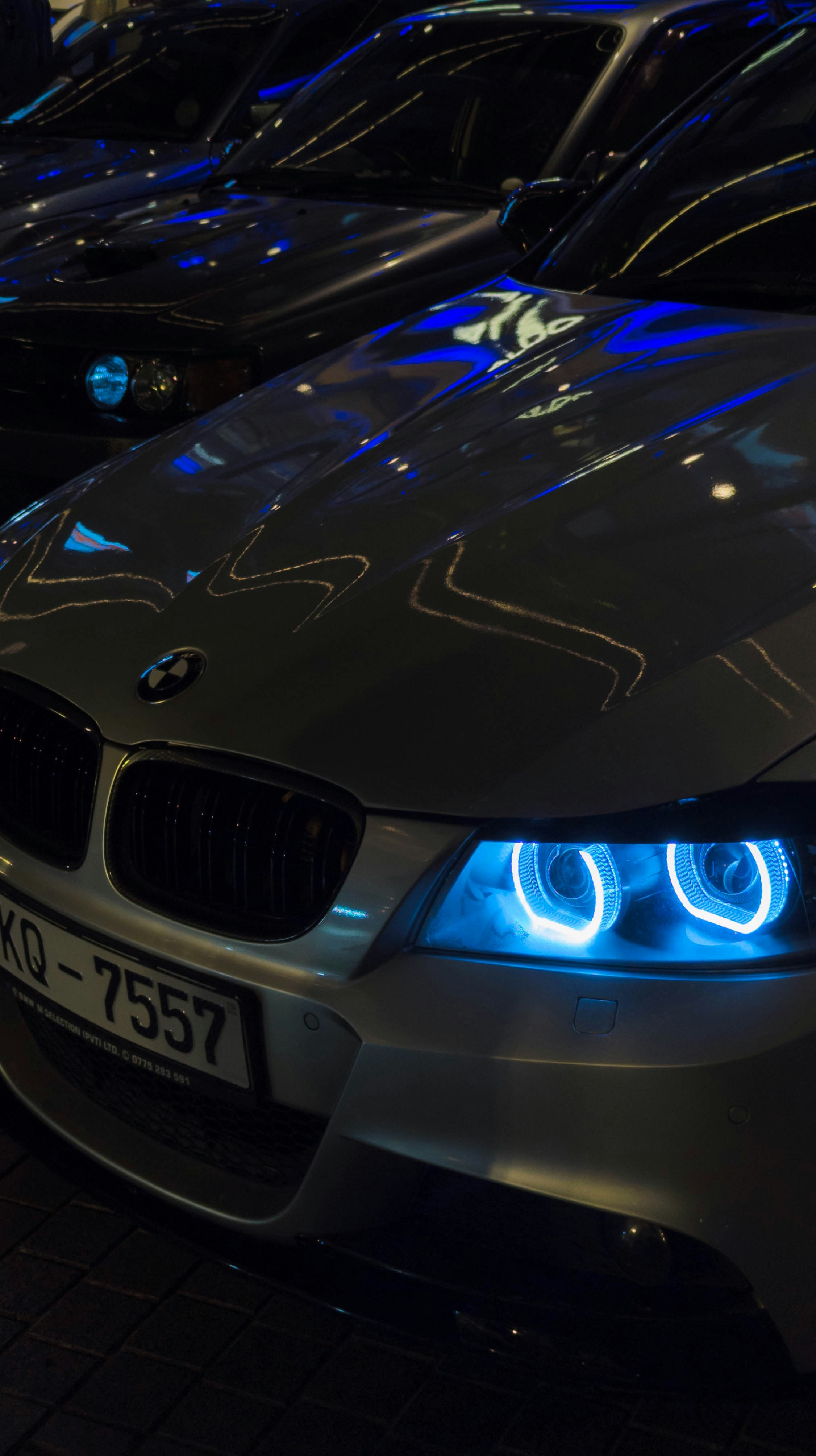 BMW car with glowing blue headlights at night.