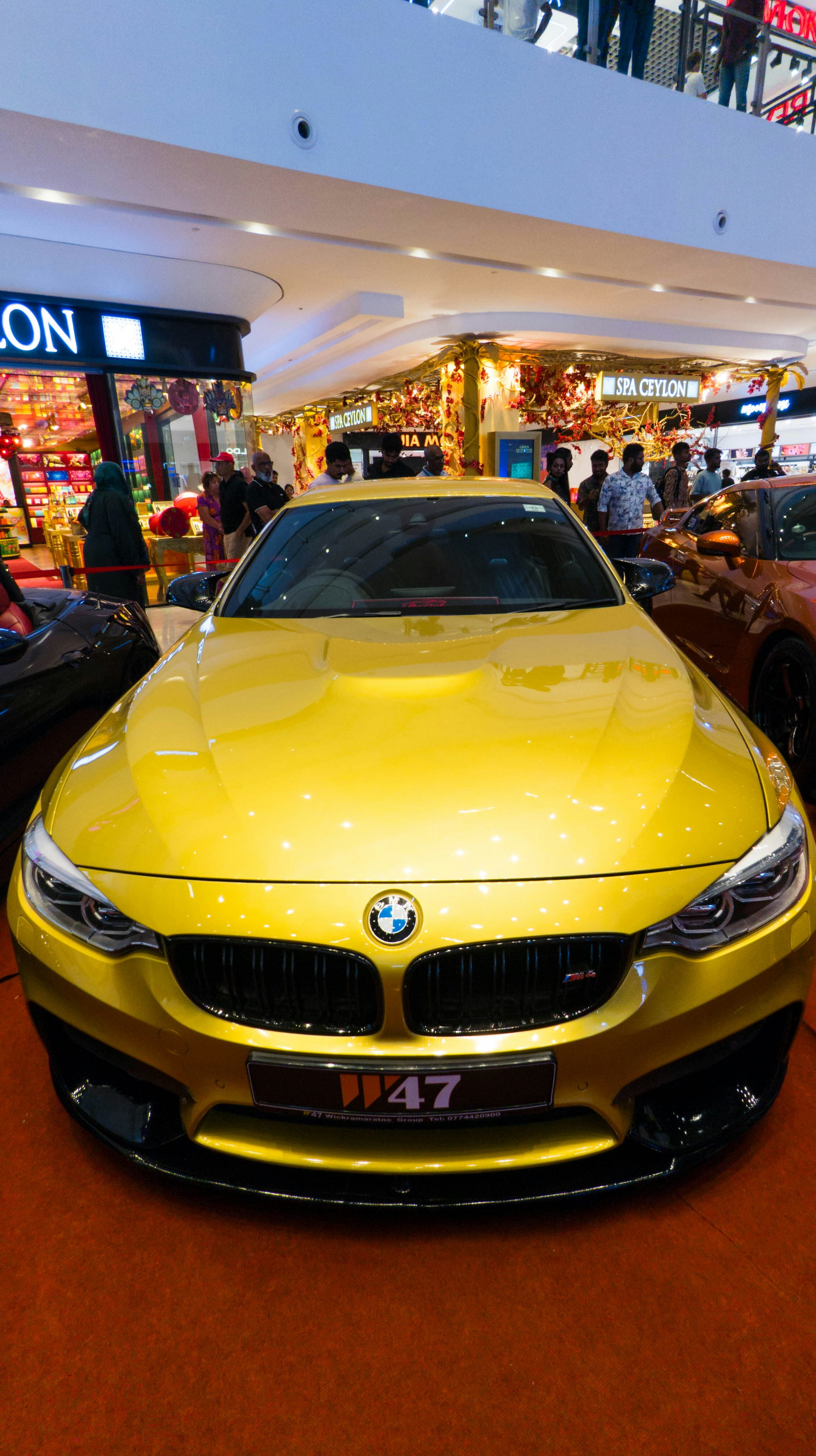 A yellow BMW m4 sits in a shopping mall.