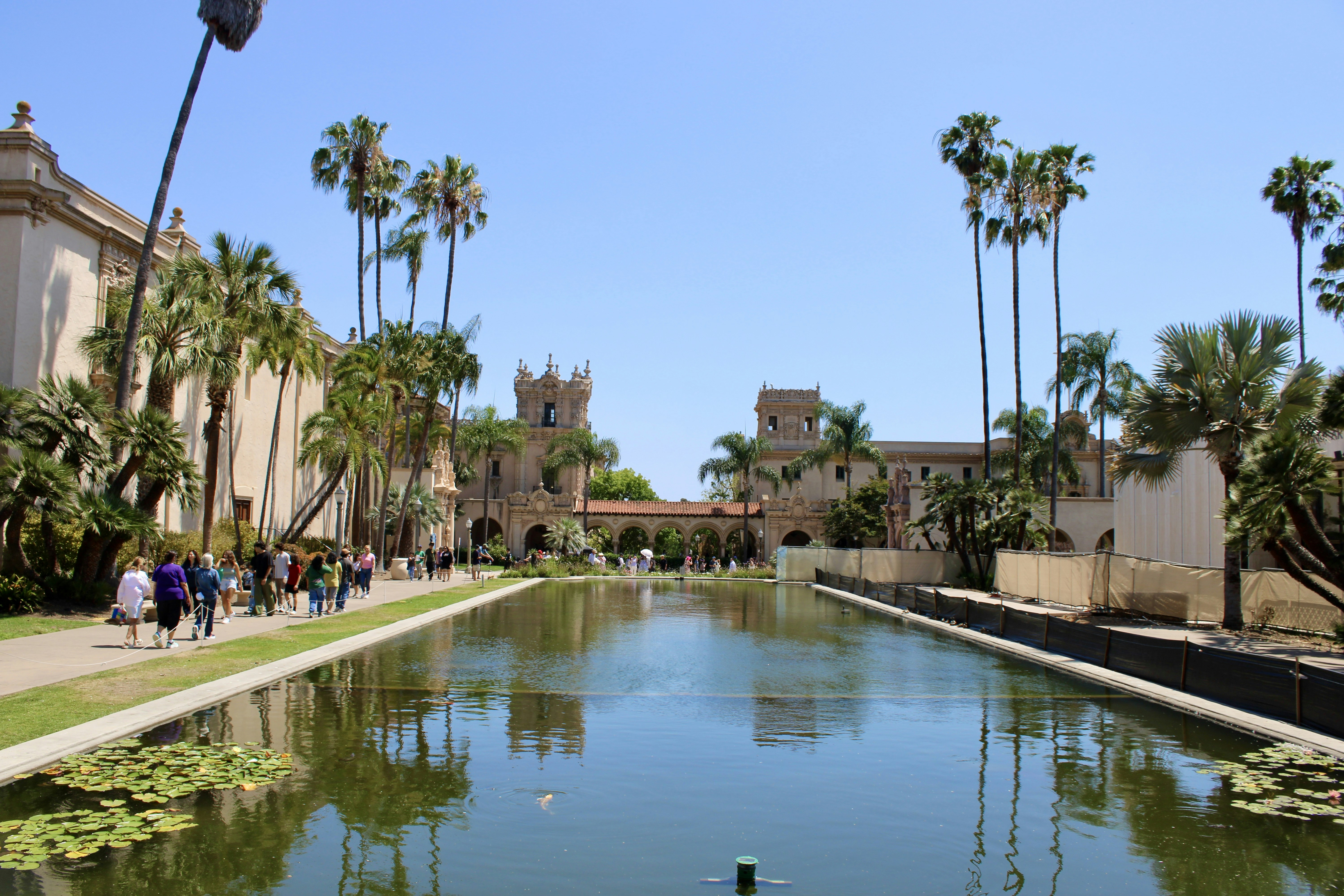 A scenic view with a pond, buildings and palm trees.