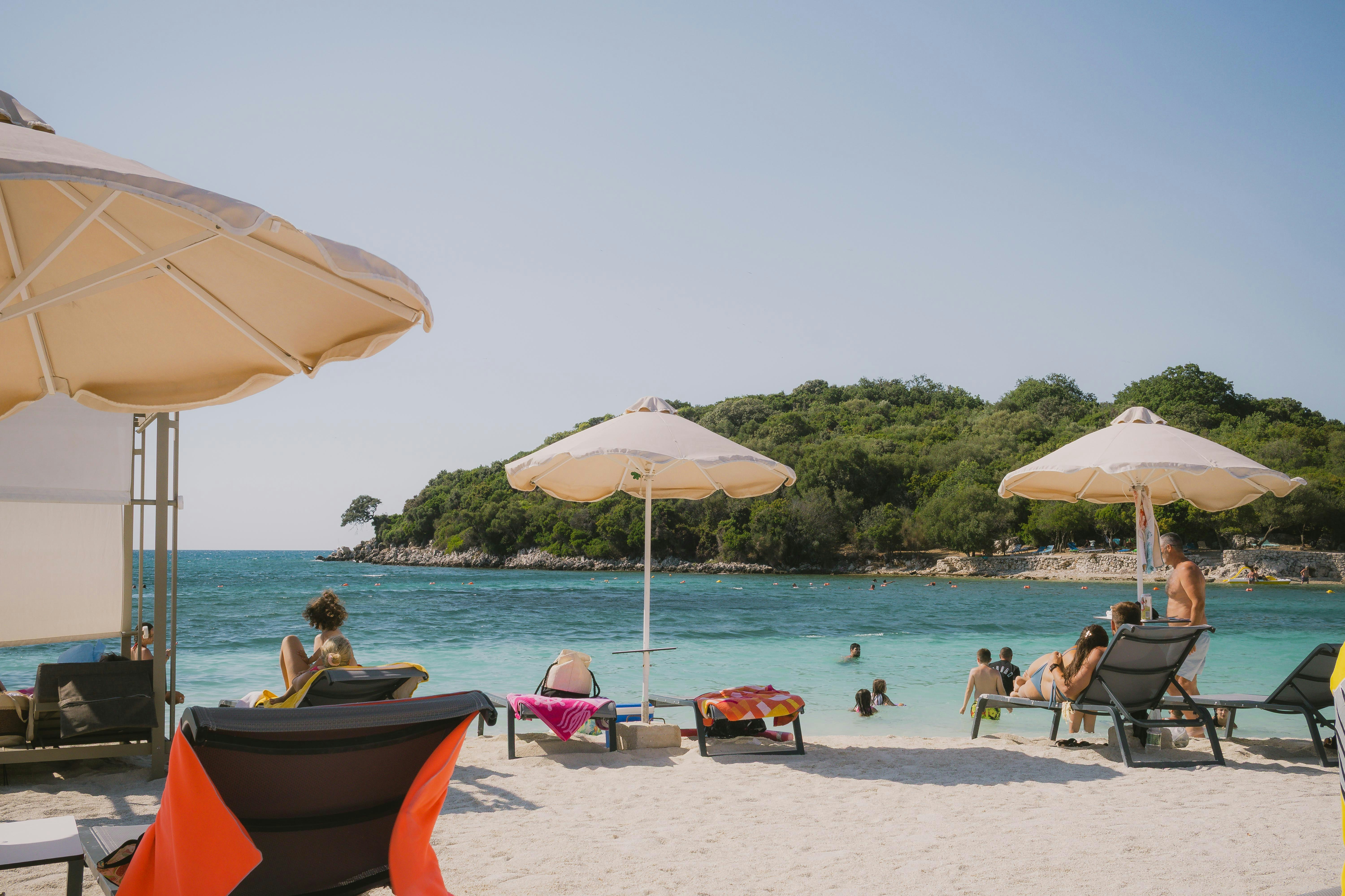 Tourists enjoying Ksamil Beach with sunbeds and umbrellas