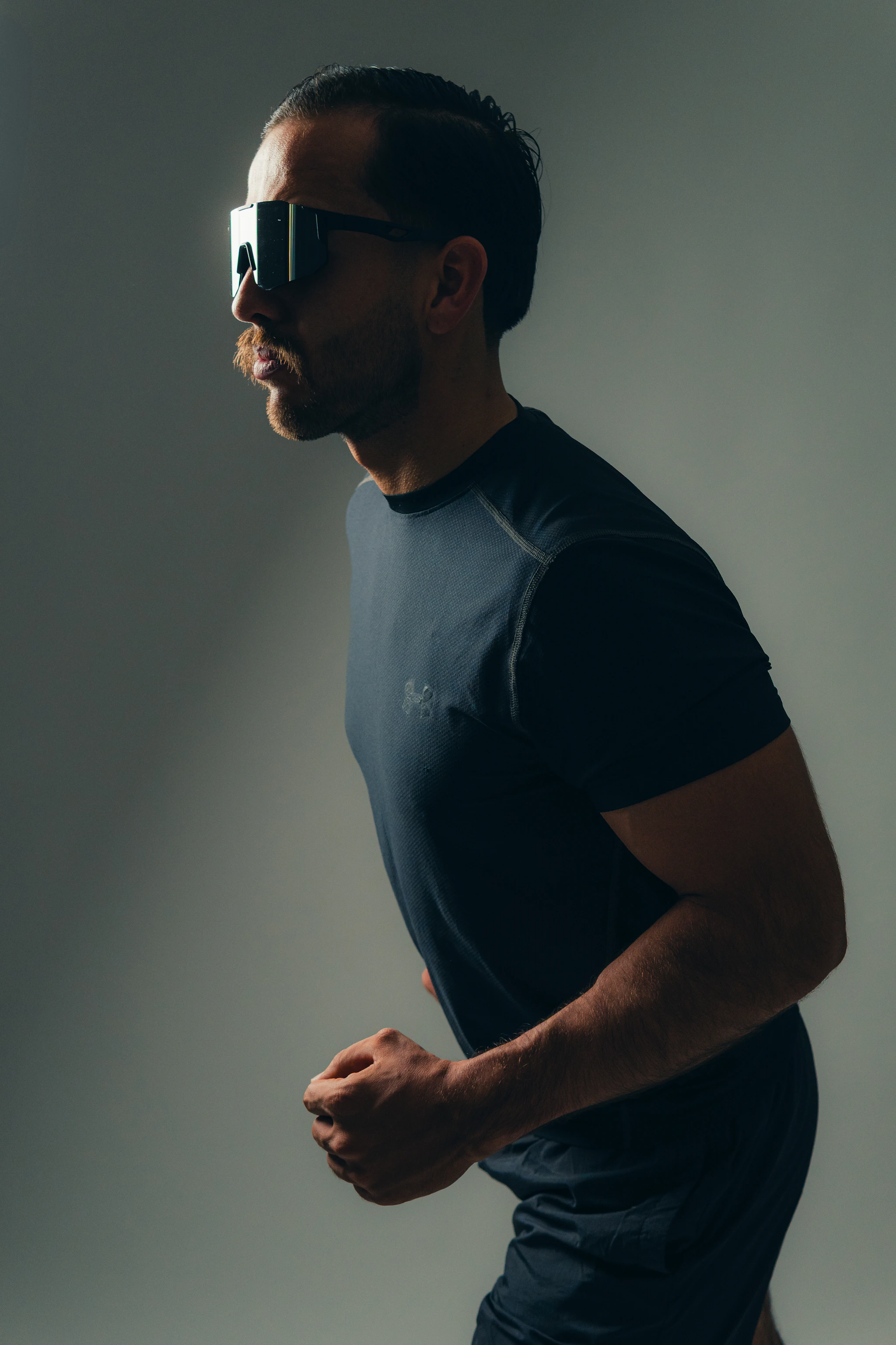 Läufer mit Sonnenbrille in Funktionsshirt bei sommerlichem Training im Freien