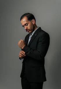 A man in a suit adjusts his sleeve.