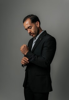 A man in a suit adjusts his sleeve.