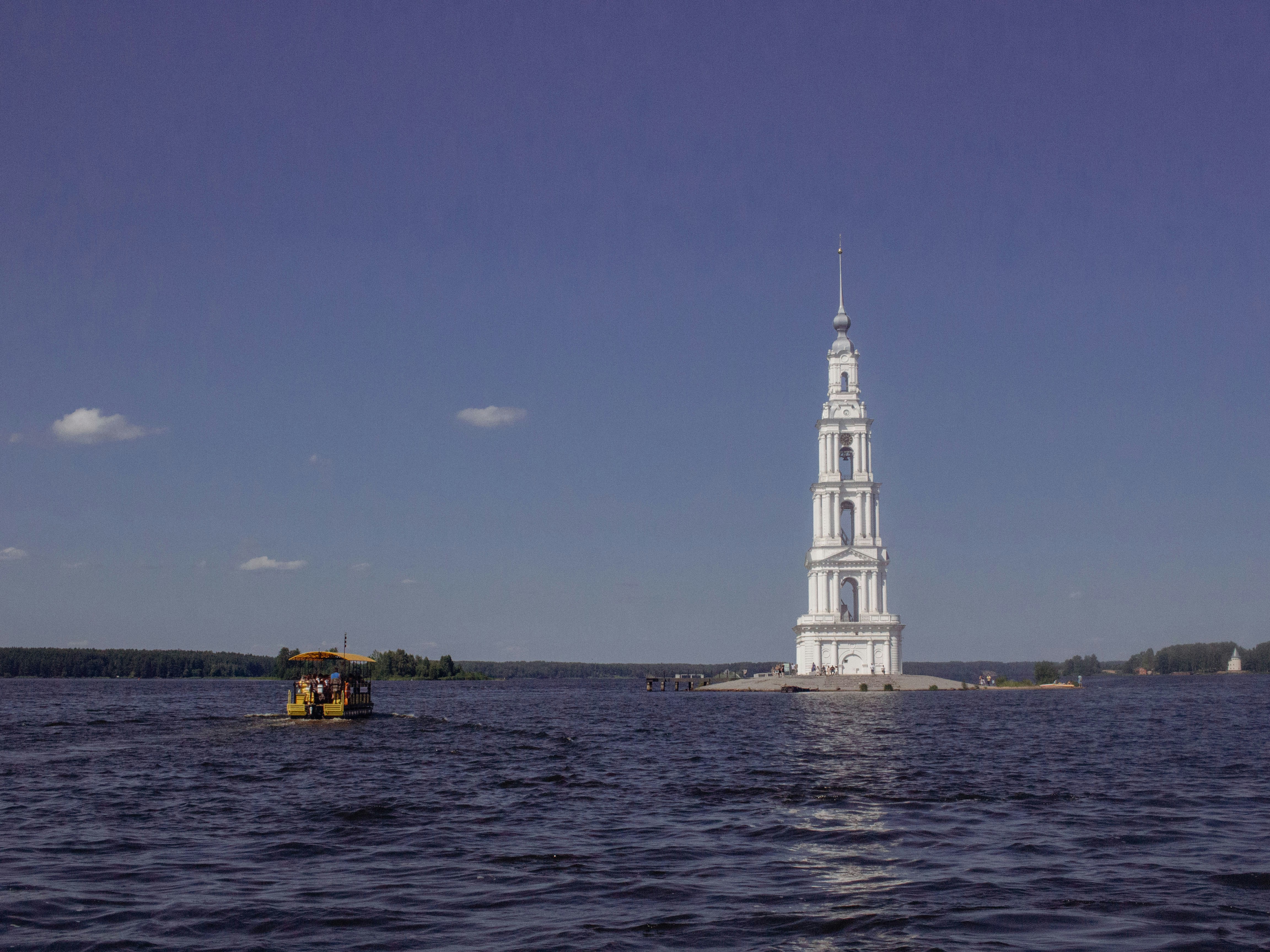 A tall white tower stands in a vast body of water.