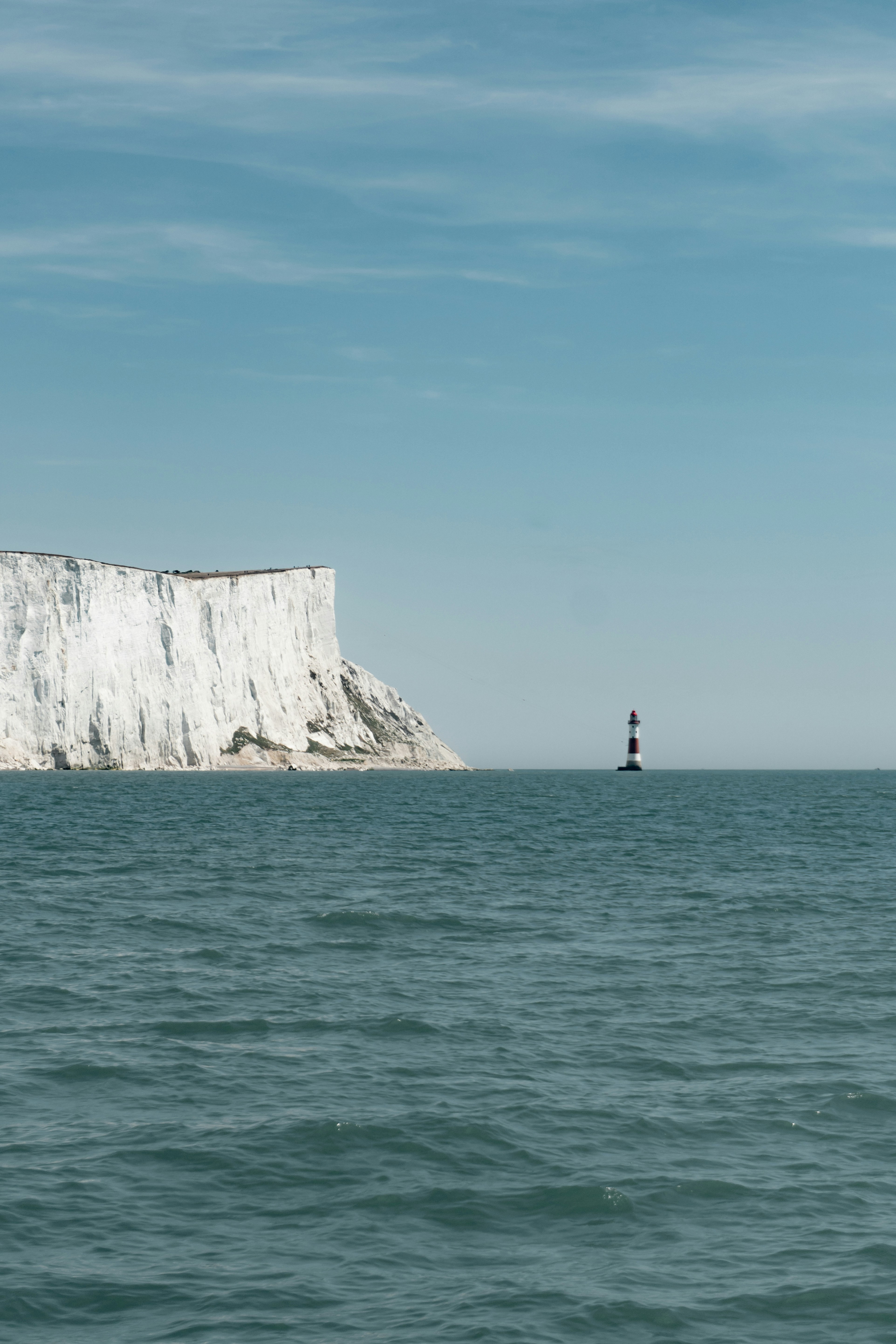 White cliffs and a lighthouse stand by the ocean.