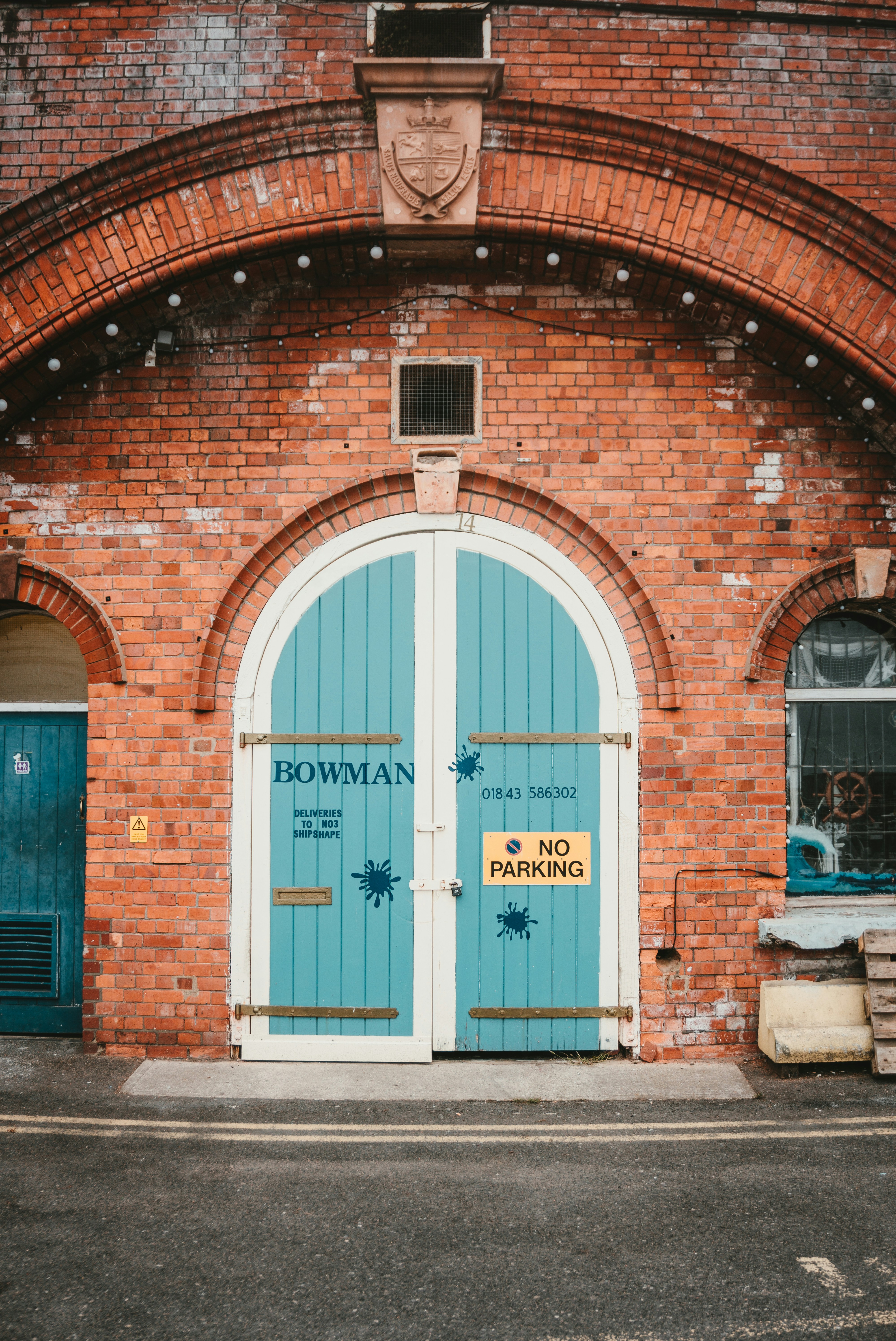 A brick building features arched blue doors.