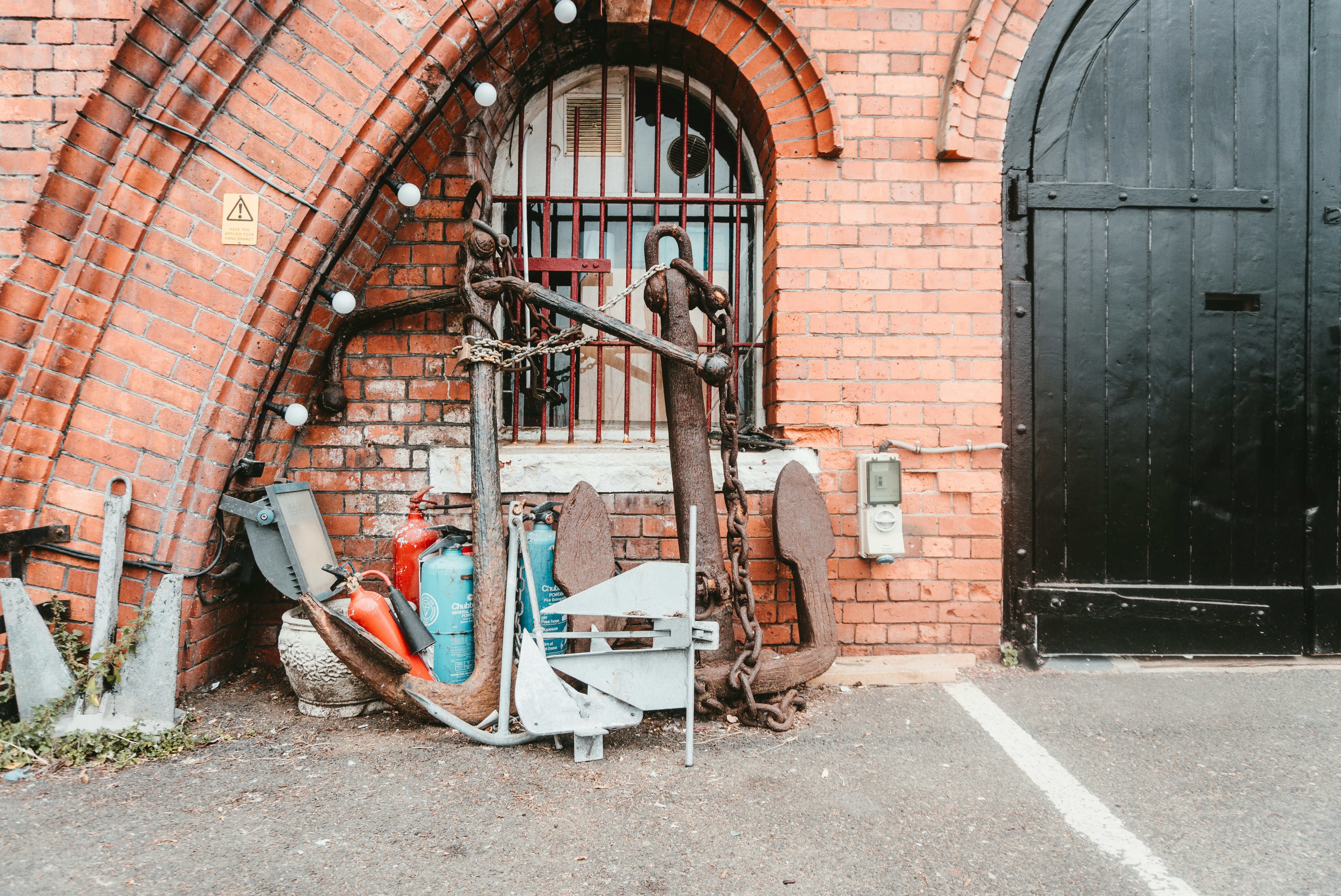 An old anchor rests against a brick wall