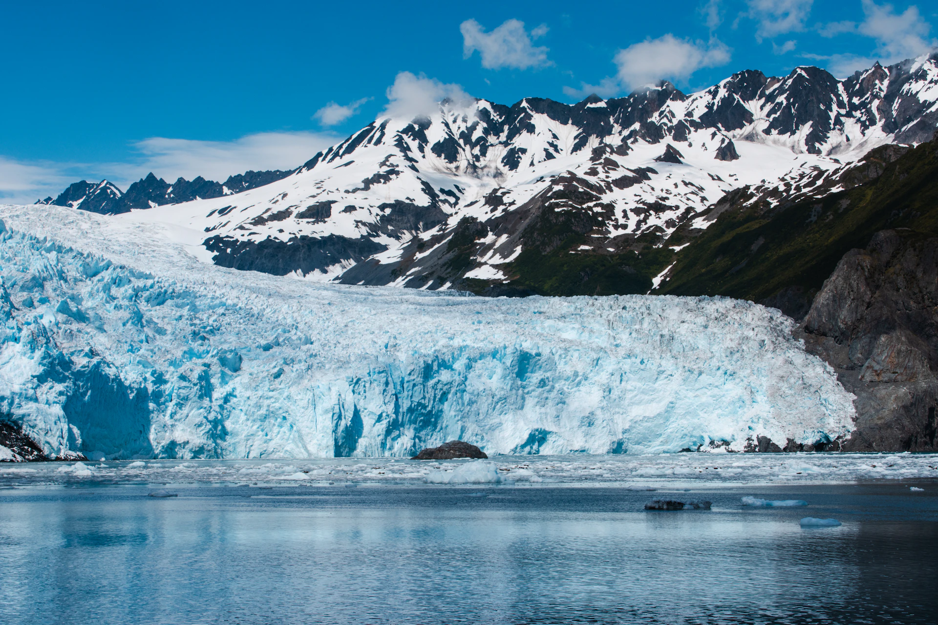 A glacier majestically meets the snowy mountains.