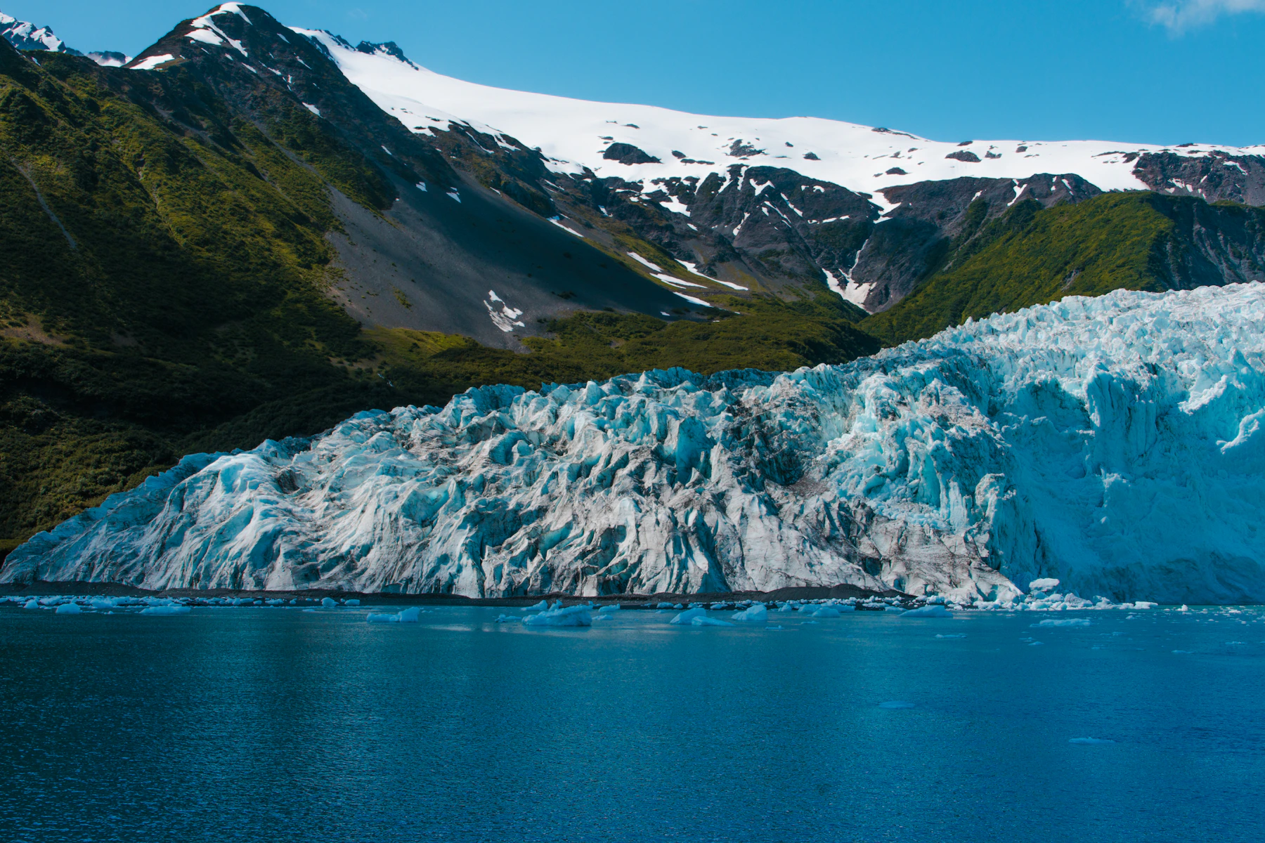 An Alaskan glacier meeting the ocean beneath rugged mountains