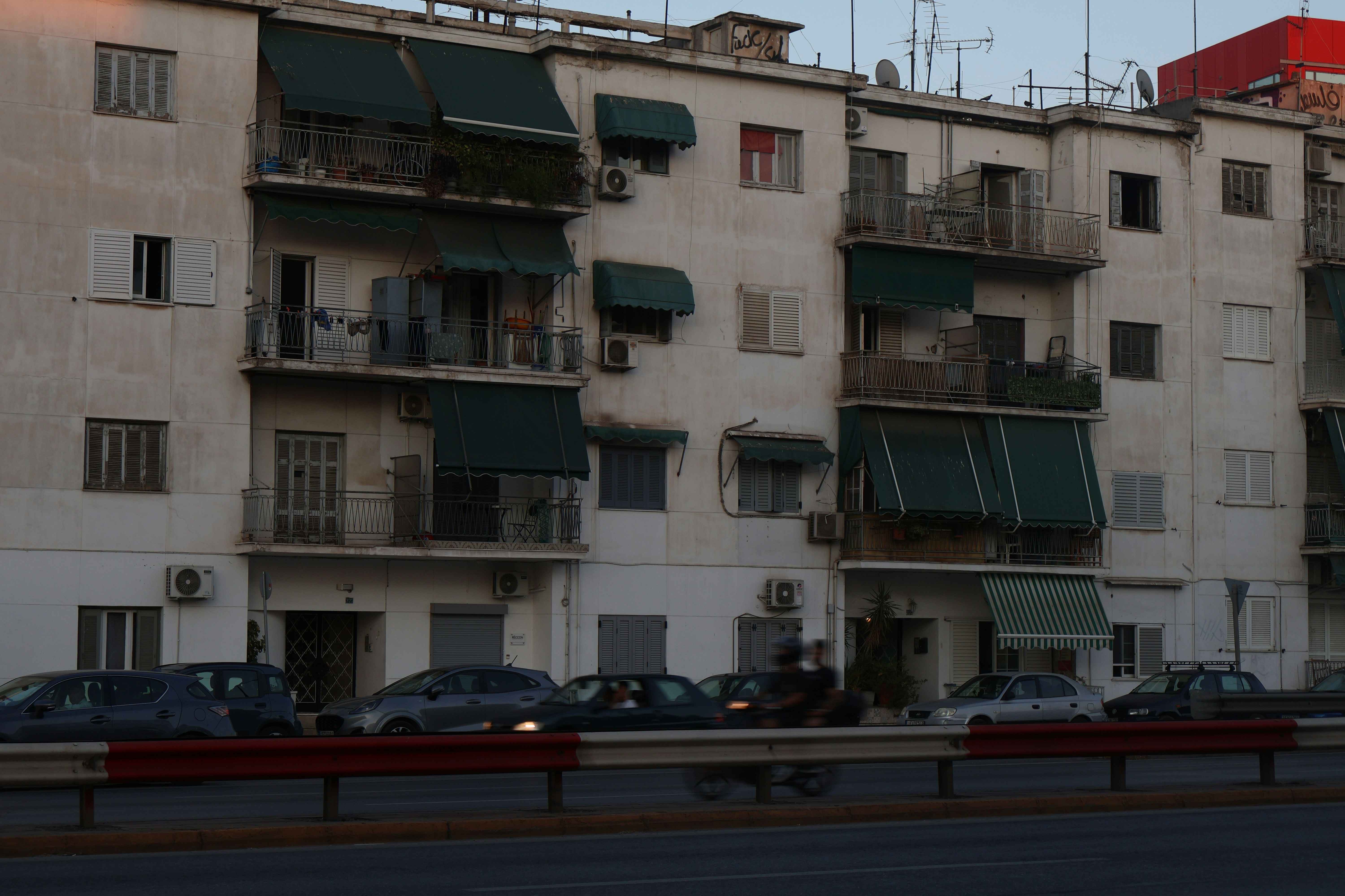 An apartment building with balconies and parked cars