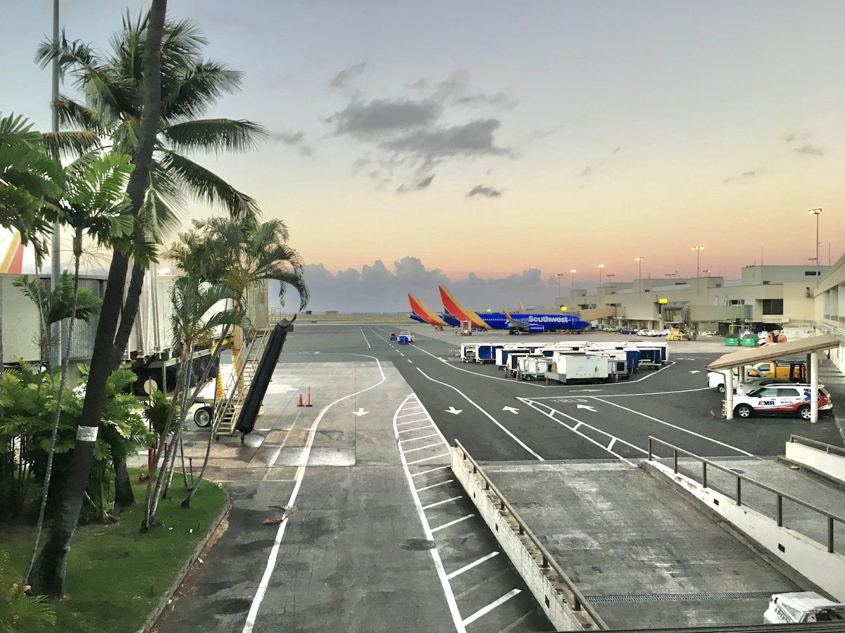 An airliner on the ground at a Hawaiian airport with mountains behind