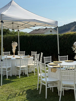 Wedding tables are set up outdoors under a canopy.