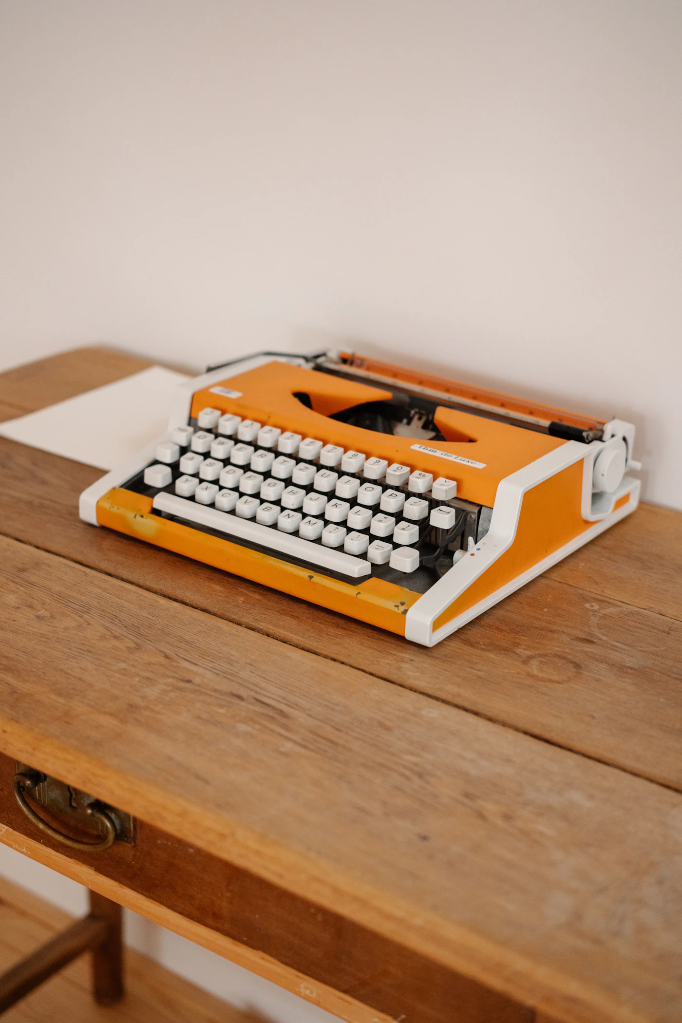 An orange vintage typewriter on a wooden desk