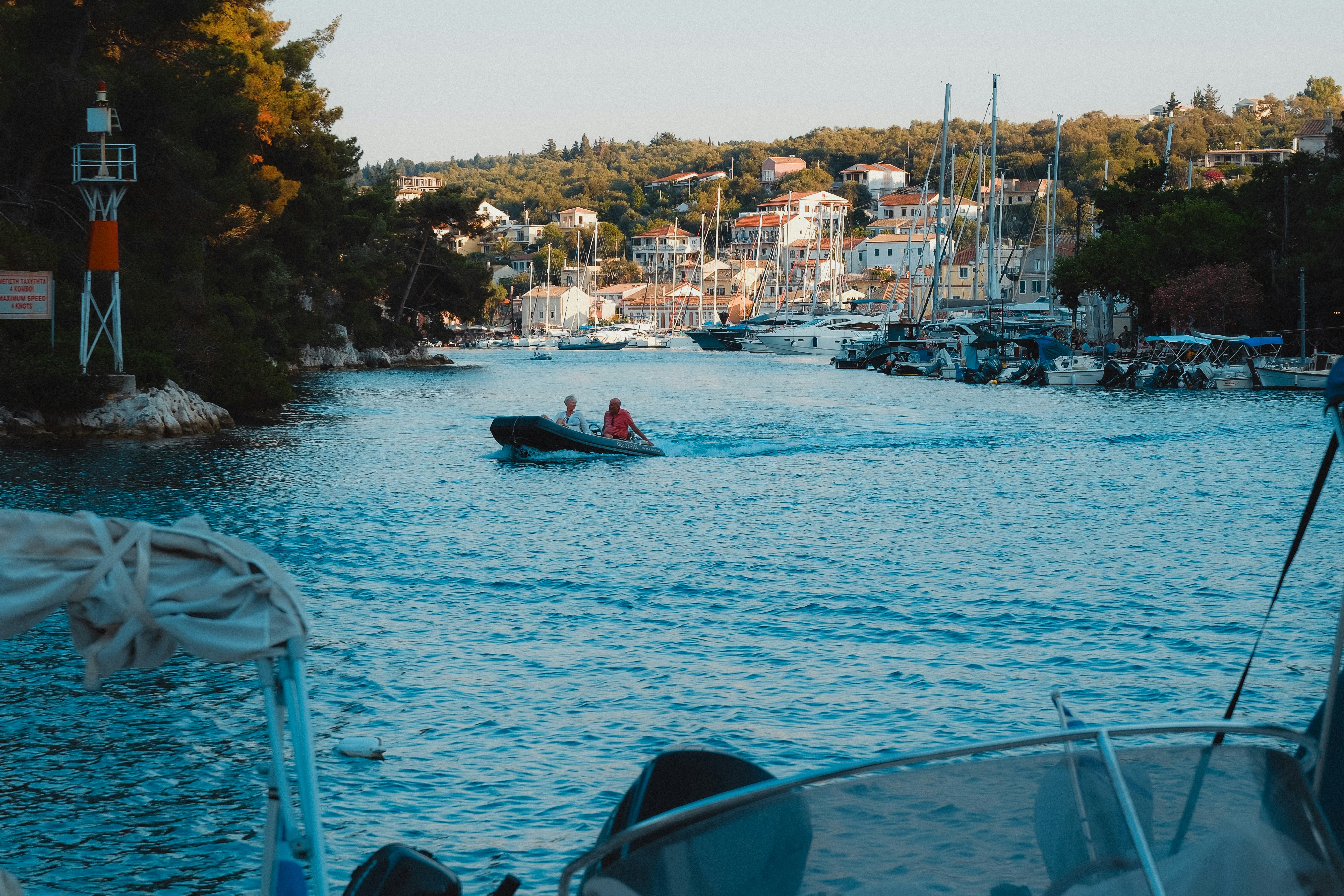 Una barca entra in un porto vicino a una città panoramica.