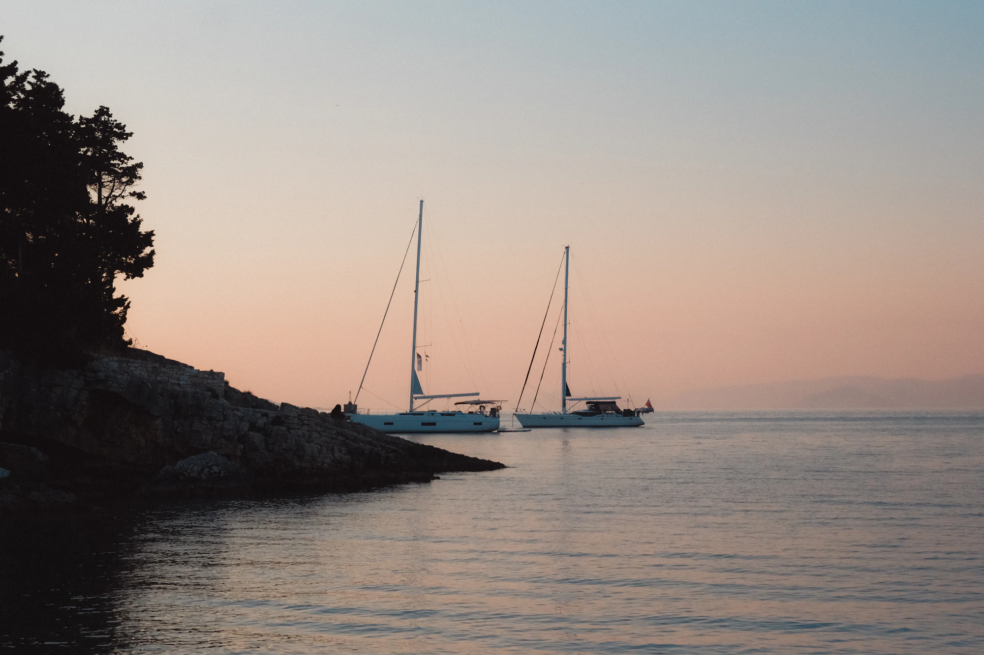 A catamaran lit from within, at anchor at dusk