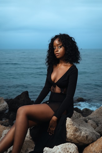 A woman poses by the sea at twilight.