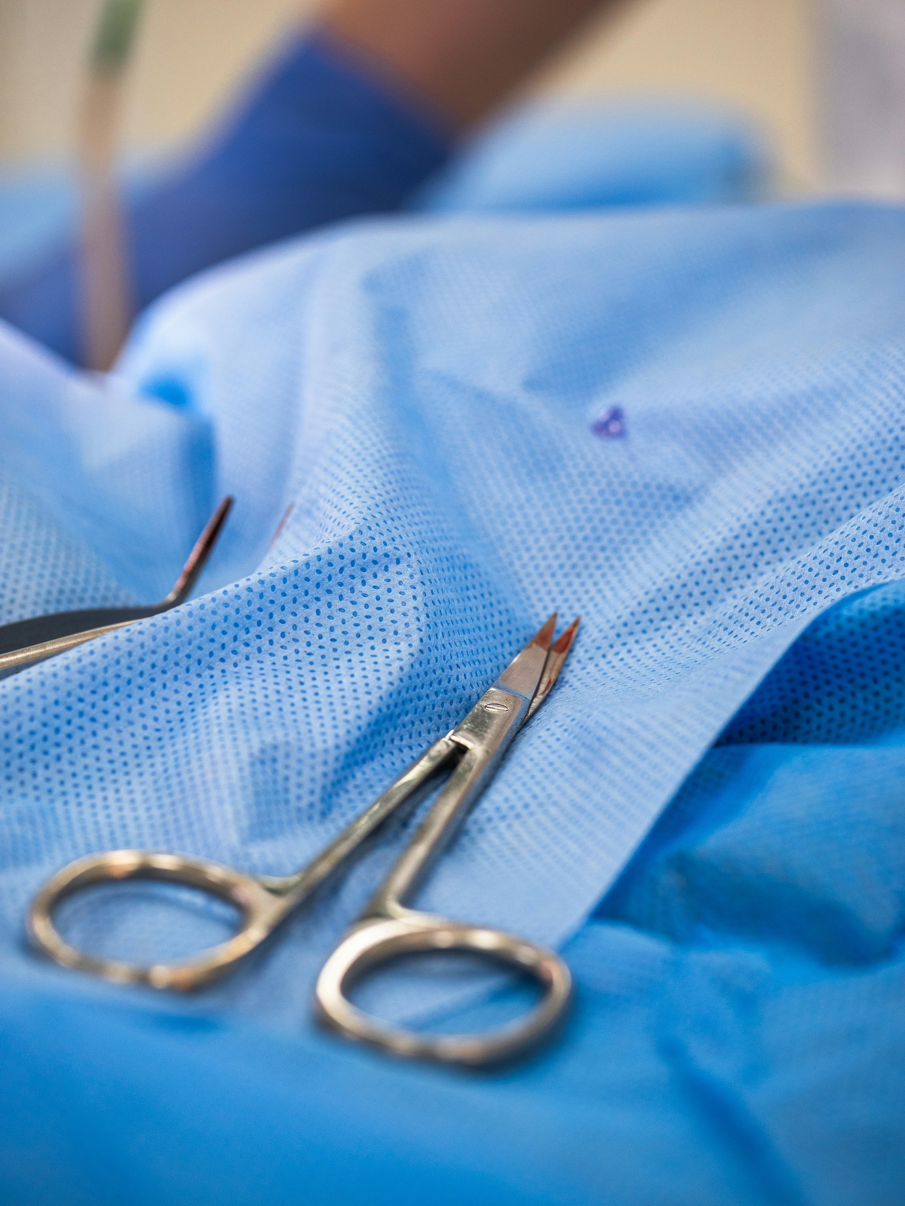 Surgical instruments sit on a blue drape.
