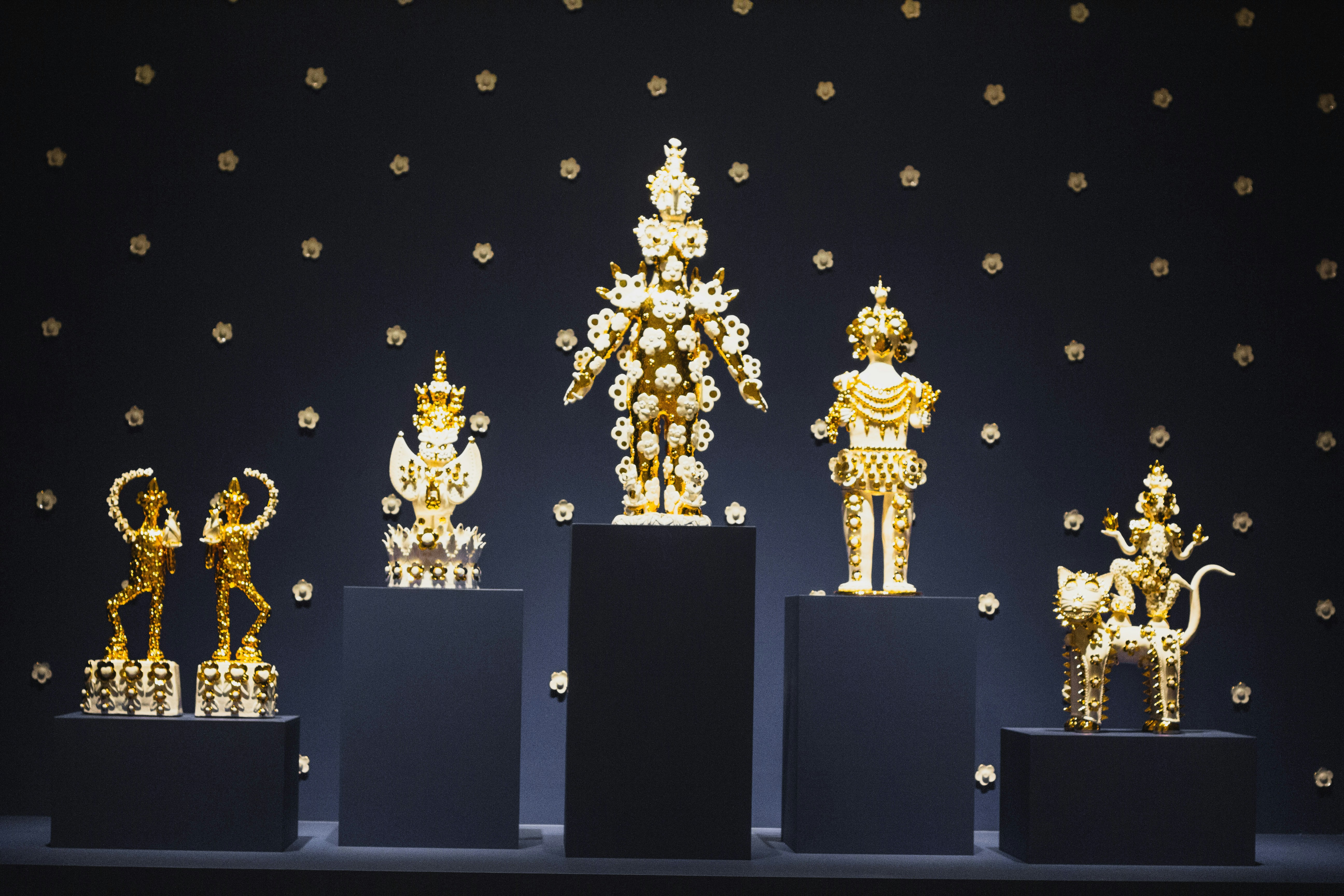 Goldene Statuen sind auf schwarzen Sockeln ausgestellt.