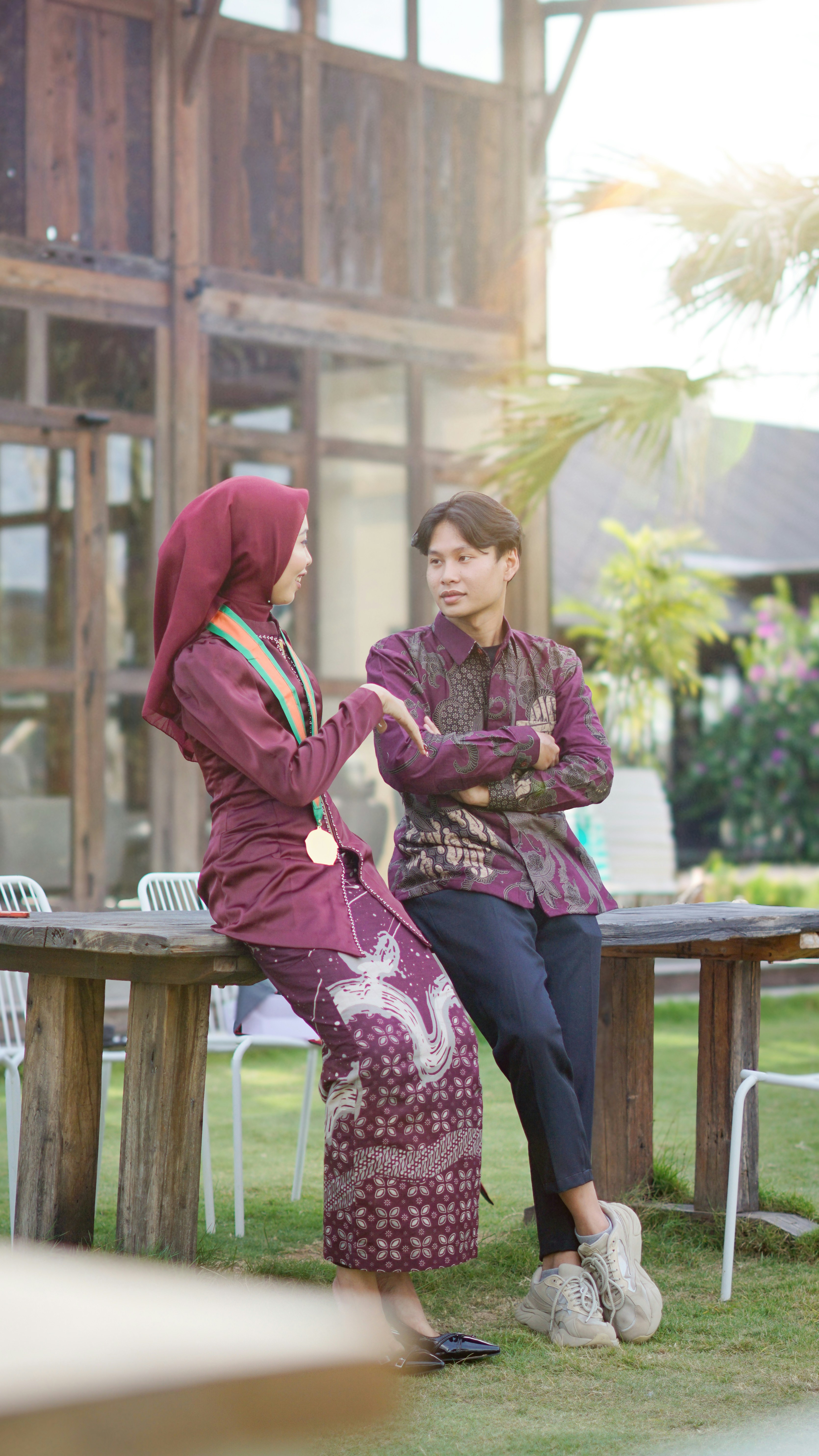 A couple in traditional outfits is talking outdoors.