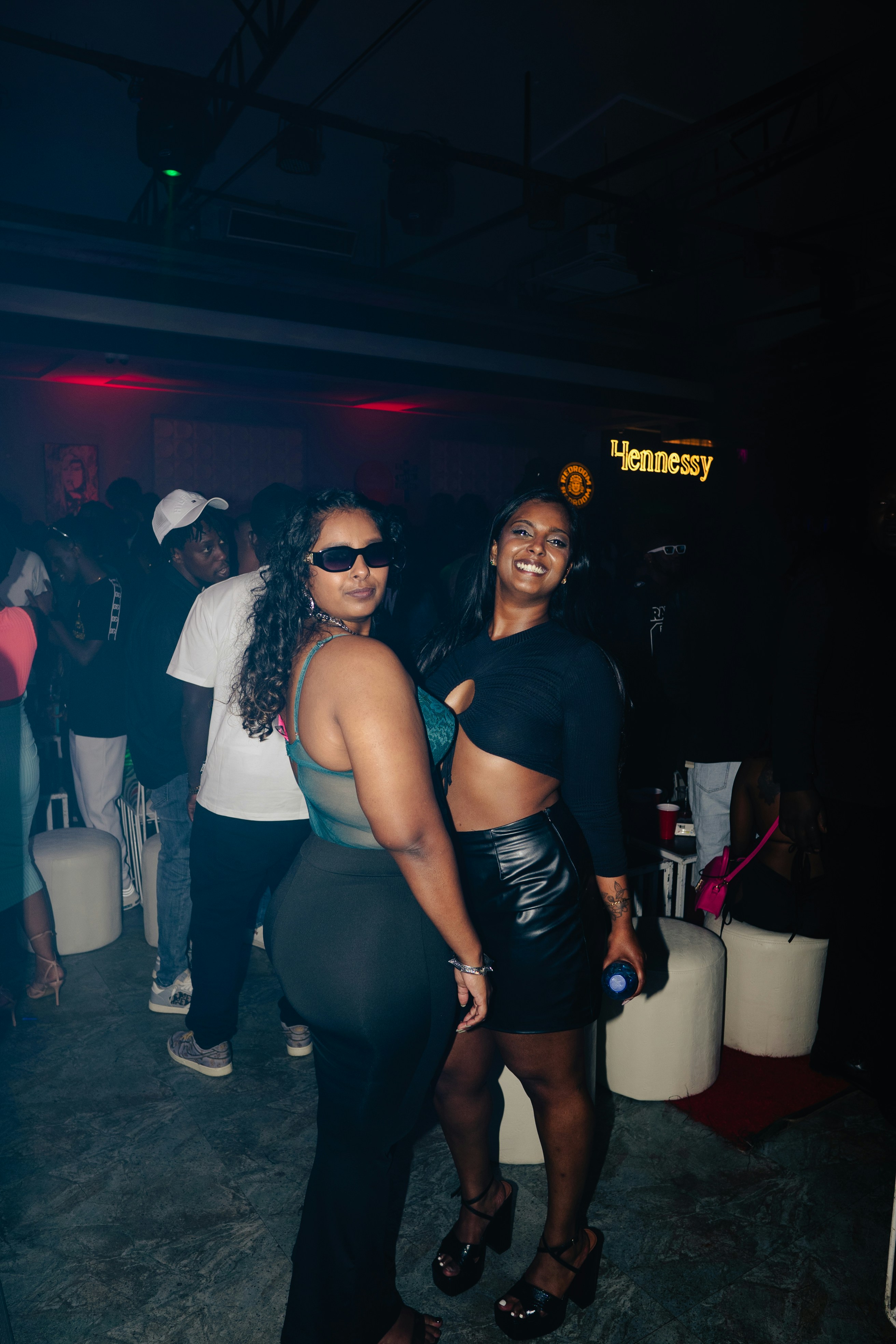 Two women pose and smile at a nightclub.