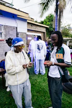 Two people are conversing at an outdoor gathering.