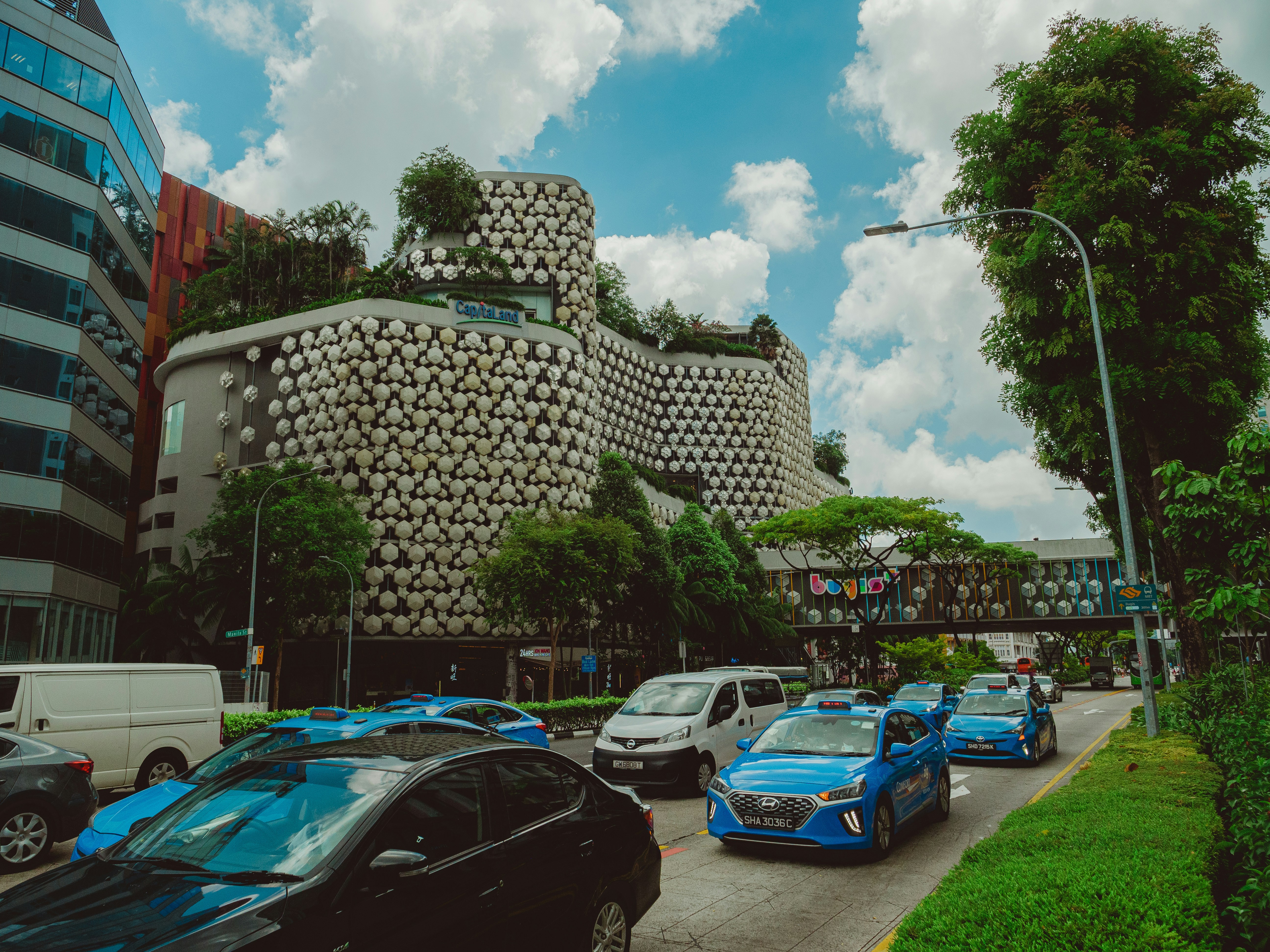 Cars drive past a unique modern building.