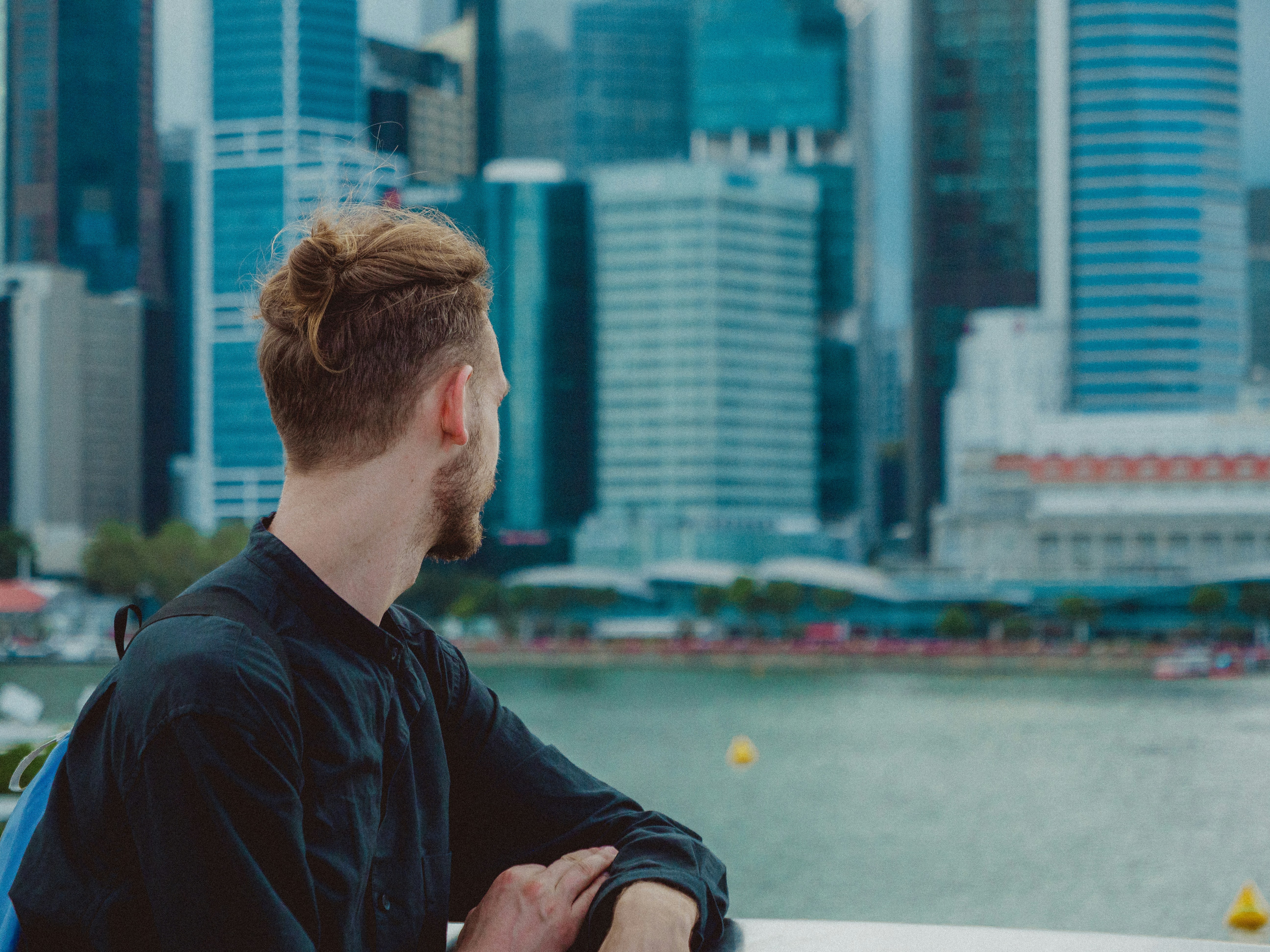 Man admires a city skyline over water.