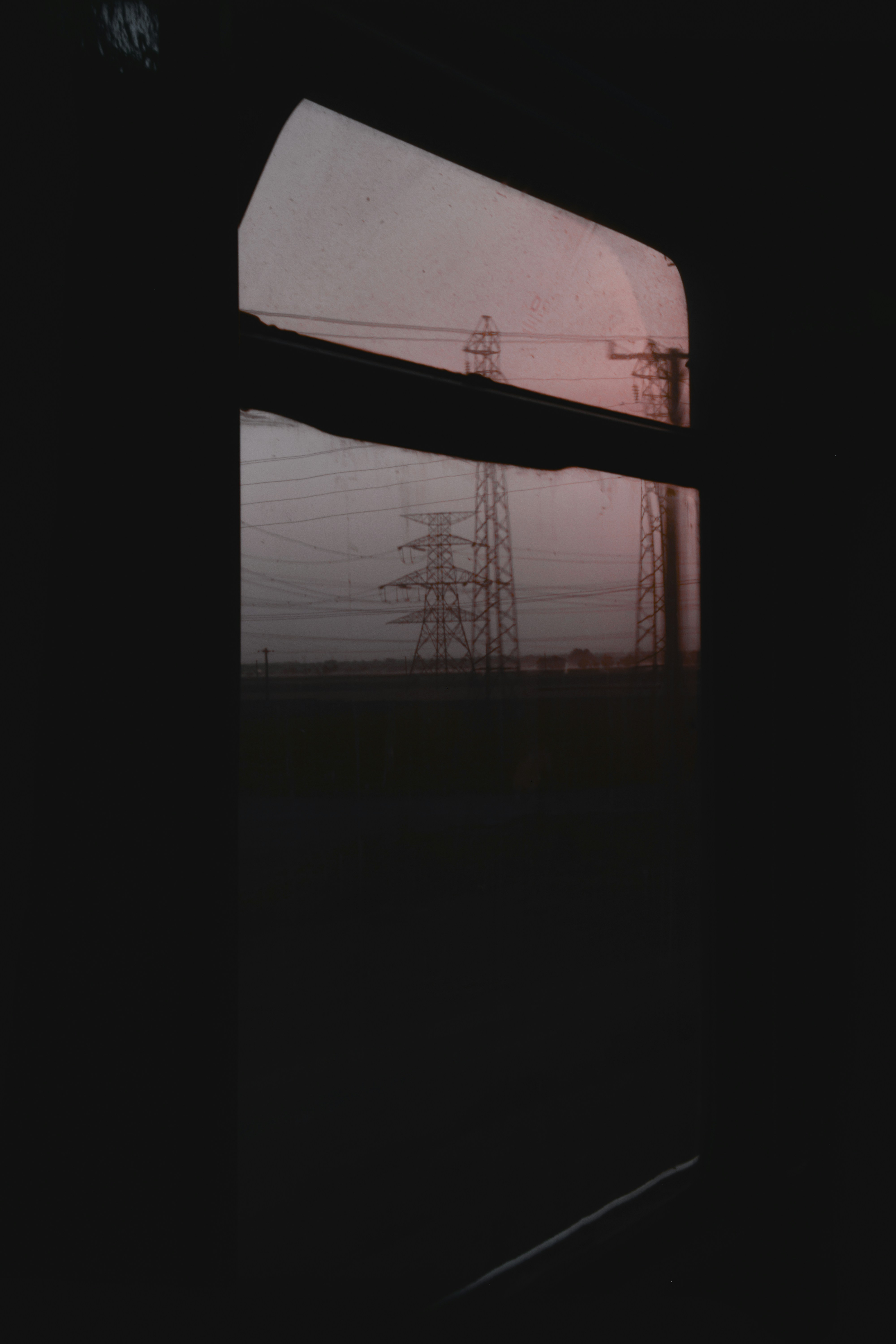 Power lines seen from a train window at dusk.